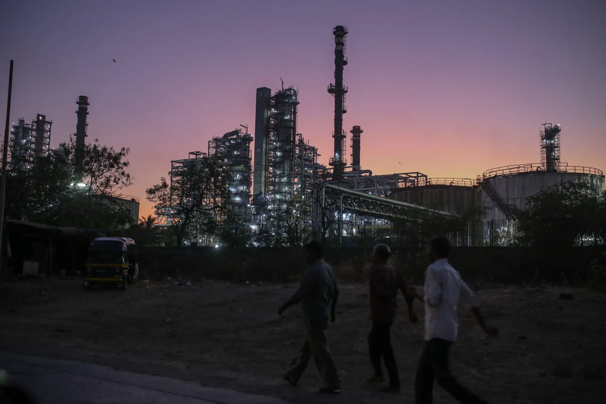 Pedestrians walk past an oil refinery in Mumbai.
