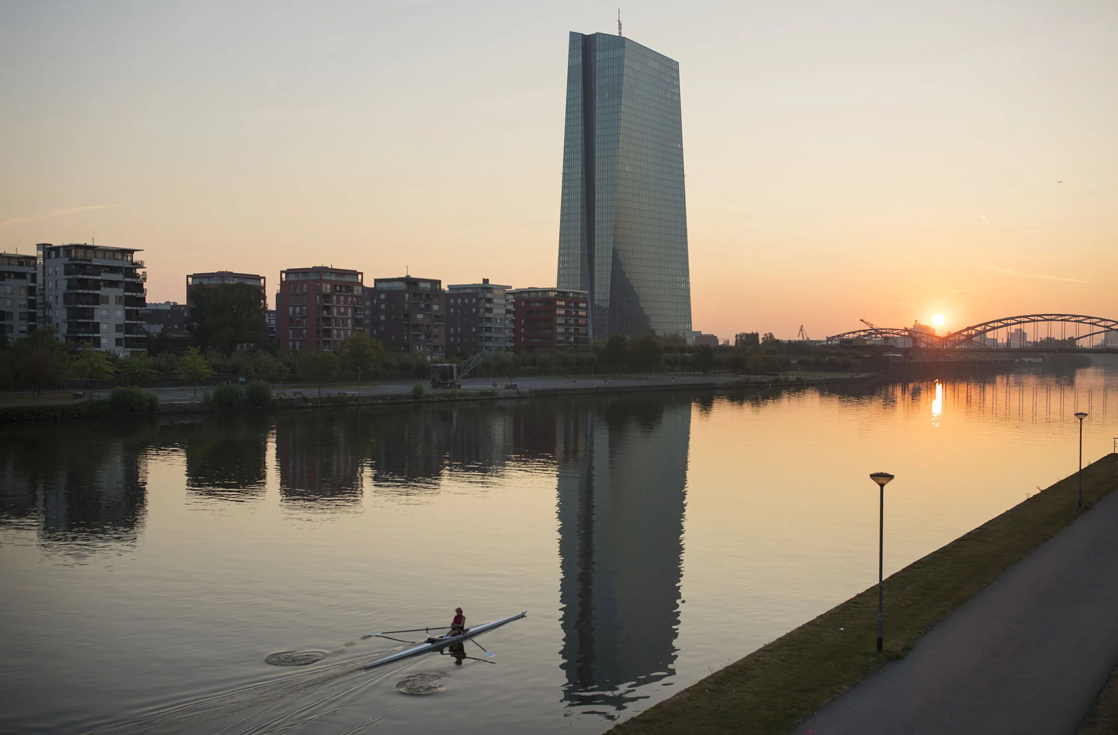 A rower paddles on the River Main as the skyscraper headquarters of the European Central Bank (ECB) stands beyond as the sun rises in Frankfurt, on Sept. 8.
