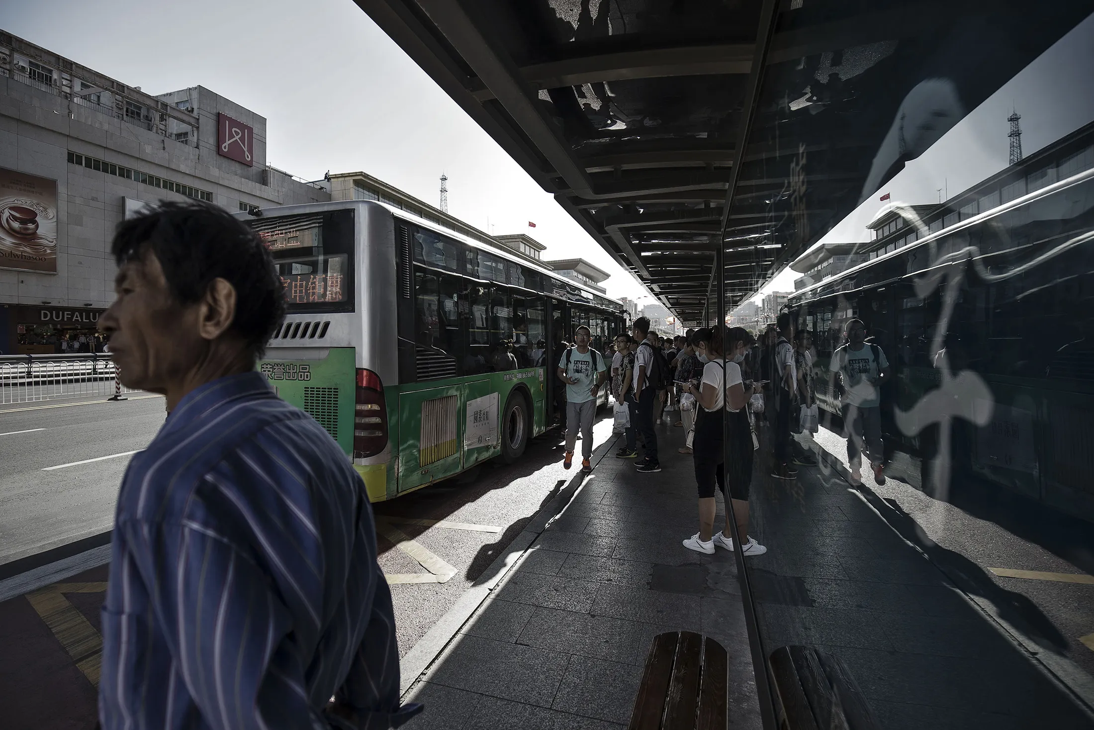 Commuters stand at a bus station in Baotou, Inner Mongolia, China, on Friday, Aug. 11, 2017. China's economy showed further signs of entering a second-half slowdown, as curbs on property, excess borrowing and industrial overcapacity began to bite.
