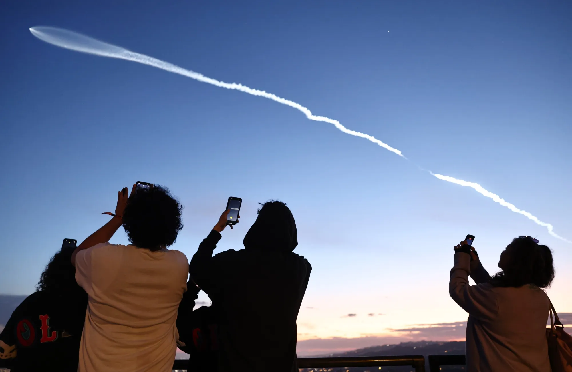 People view a SpaceX Falcon 9 rocket carrying 22 Starlink internet satellites into space after launching from Vandenberg Space Force Base in Los Angeles in 2024.