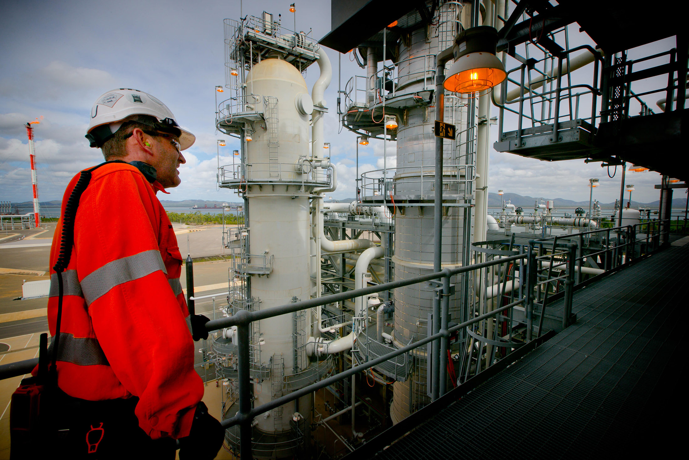 A worker crosses a walkway at a plant at the Queensland Curtis Liquefied Natural Gas (QCLNG) project site, operated by QGC Pty, a unit of Royal Dutch Shell Plc, in Gladstone, Australia, on Wednesday, June 15, 2016. Gas from more than 2,500 wells travels hundreds of miles by pipeline to the project, where it's chilled and pumped into 10-story-high tanks before being loaded onto massive ships.
