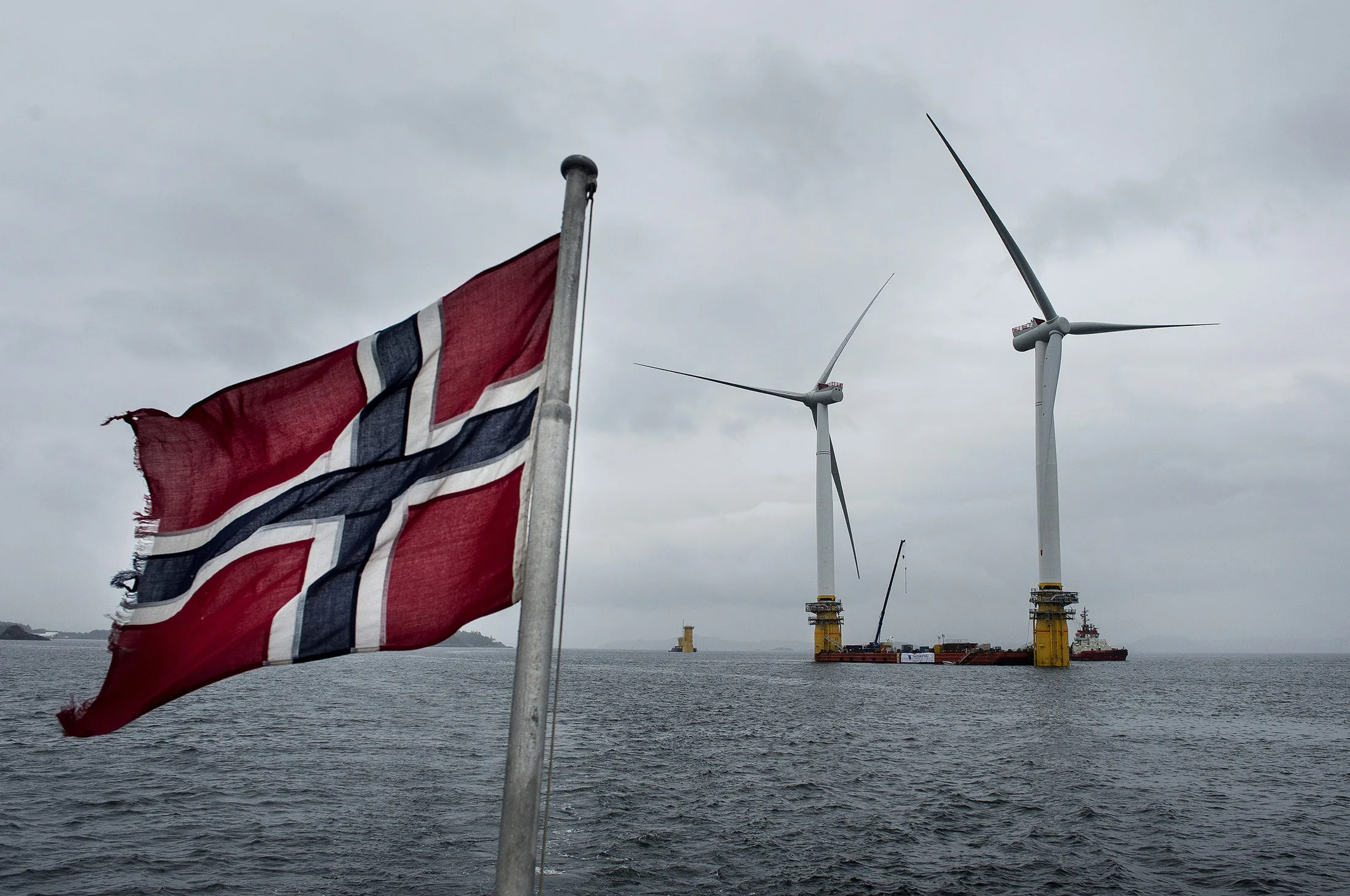 A Norwegian flag flies from a boat near the assembly site of offshore floating wind turbines in Norway.
