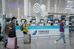 Passengers wearing protective masks walks past a self-service check-in area for China Southern Airlines Co. at Shenzhen Bao'an International Airport in Shenzhen.