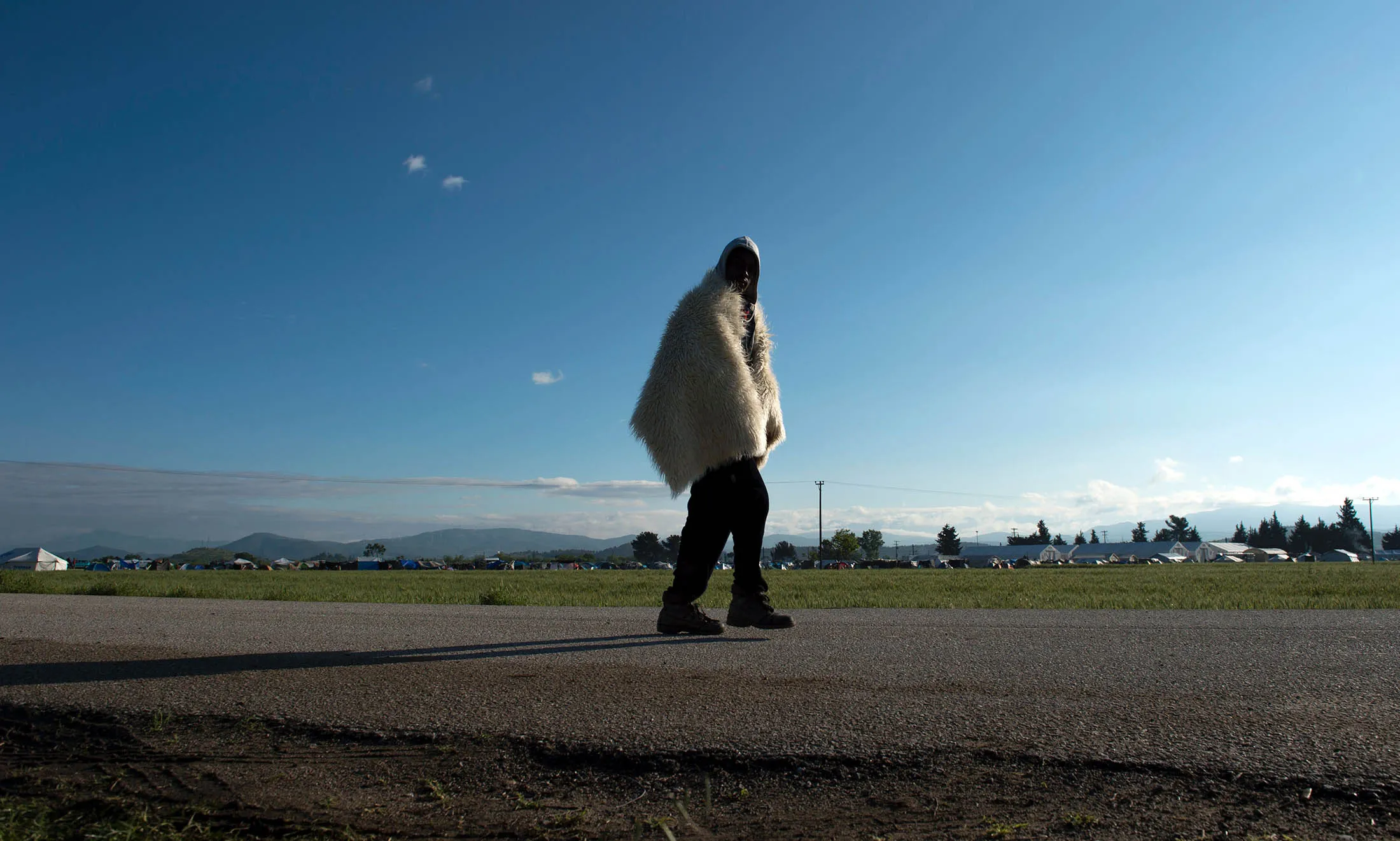 A man from Somalia wearing a blanket over his shoulders leaves a makeshift camp near the Greek-Macedonian border.
