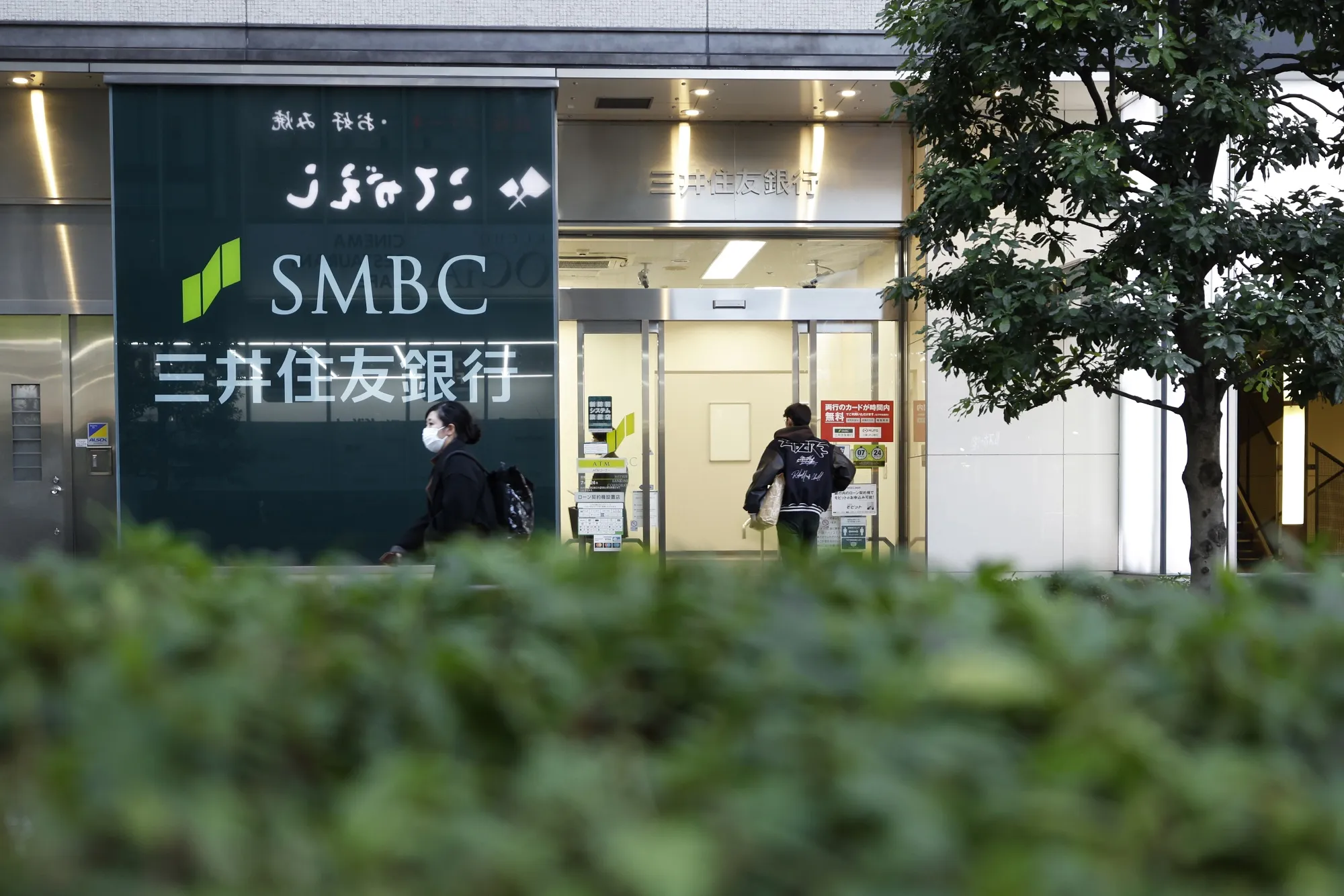Pedestrians in front of a Sumitomo Mitsui Banking Corp branch in Tokyo.