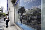 A pedestrian stands in front of an electronic stock board at a securities firm in Tokyo, Japan, on Thursday, Aug. 30, 2018.