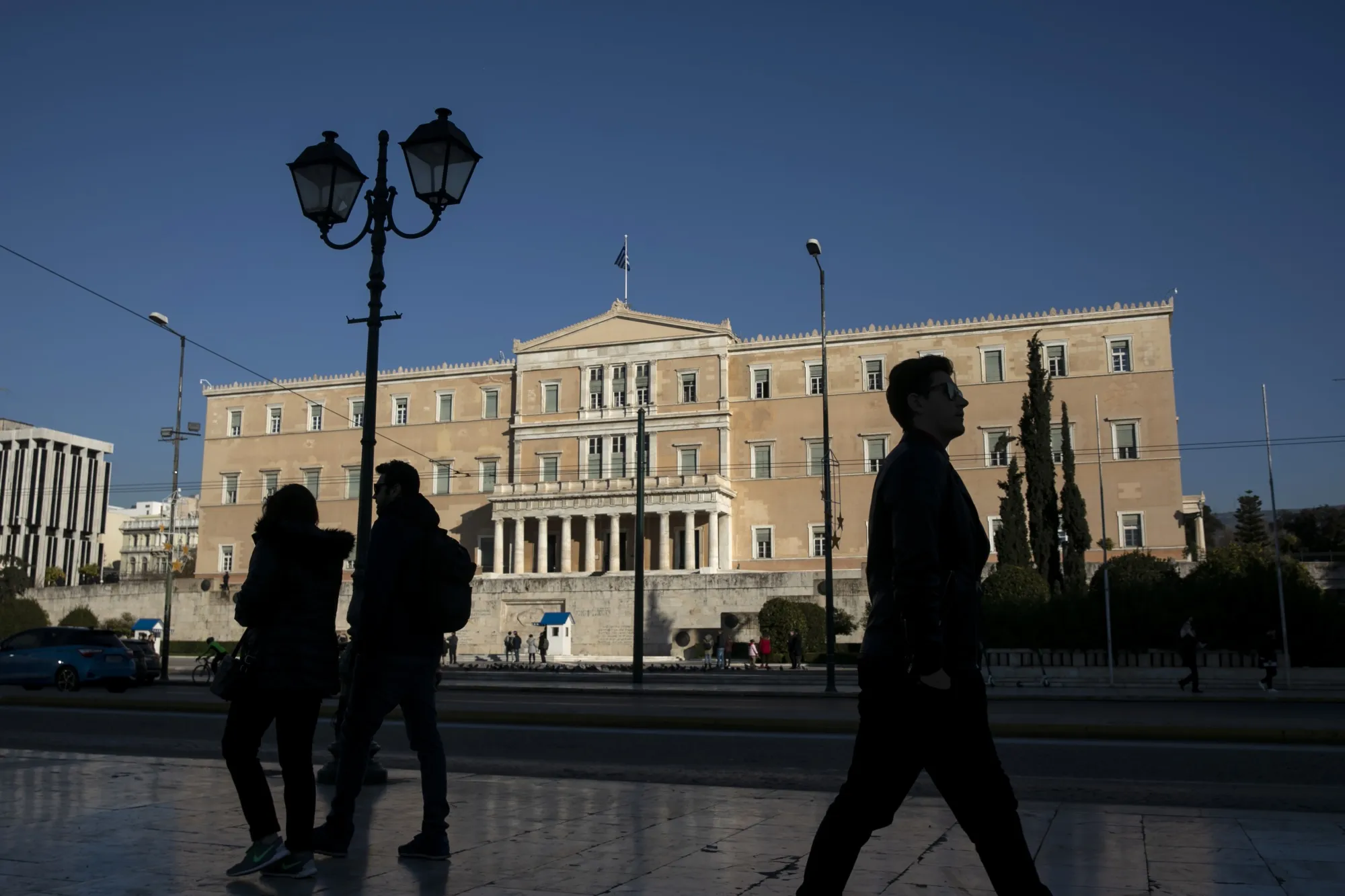 Pedestrians walk in front of the parliament in Athens.