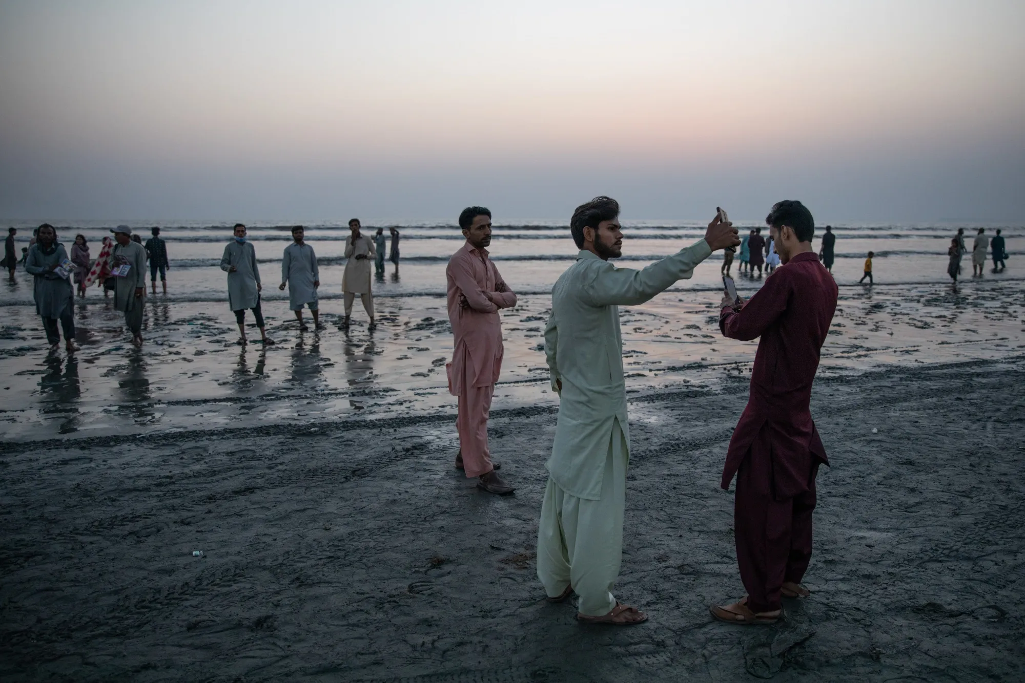 Visitors use their mobile phones at Clifton Beach in Karachi, on Nov. 12.