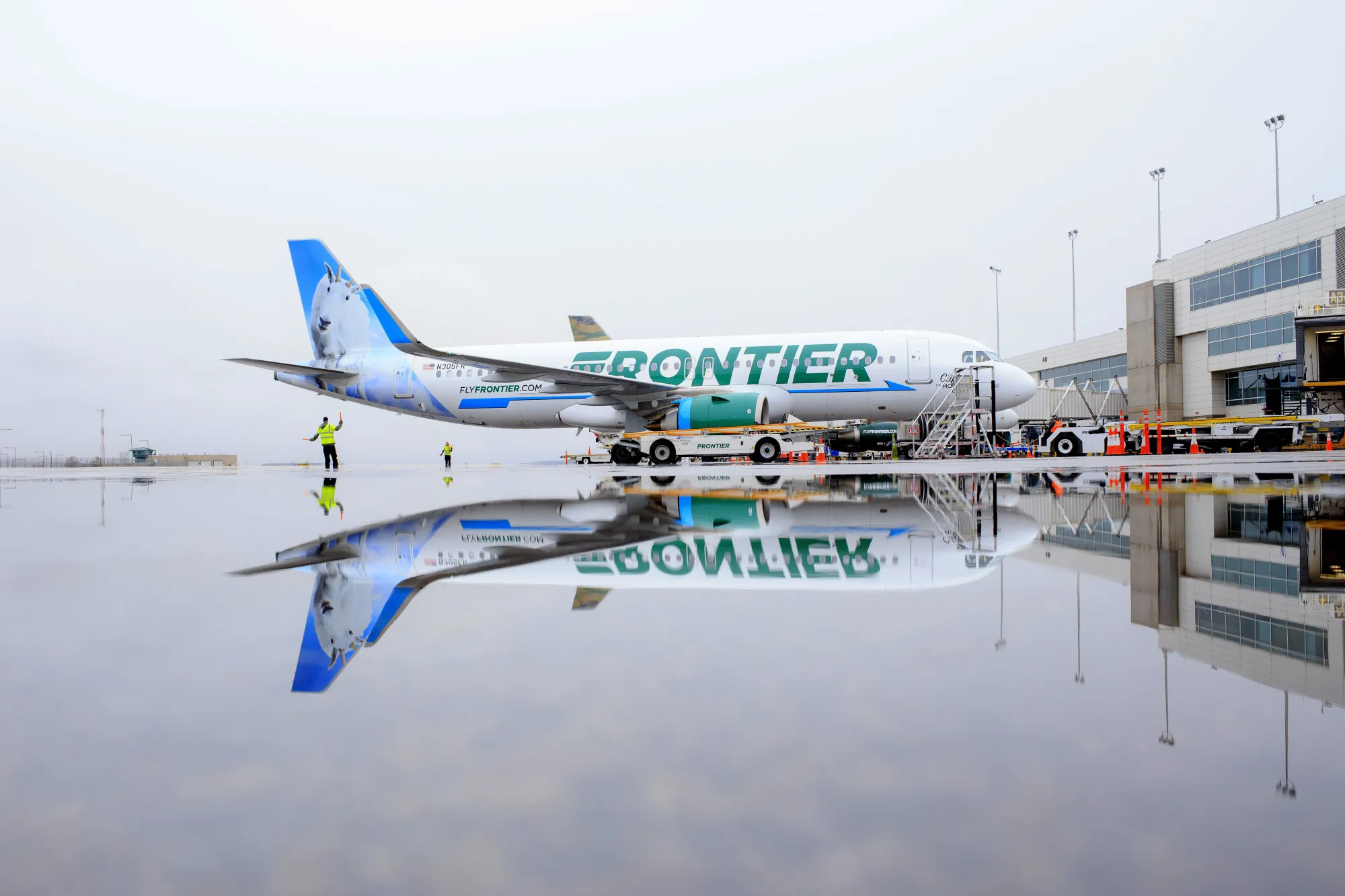 A Frontier Airlines Inc. plane is reflected in a puddle at Denver International Airport.&nbsp;