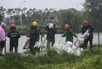 In this photo released by Xinhua News Agency, workers carry sandbags to reinforce a riverbank to prevent the river back flow caused by the approaching typhoon Muifa in Jiashan County of Jiaxing City, east China's Zhejiang Province, Wednesday, Sept. 14, 2022. Typhoon Meihua has weakened to a severe tropical storm Thursday morning, after bringing heavy rains and strong winds to Shanghai and parts of Jiangsu province overnight, according to China's National Meteorological Center.  (Xu Yu/Xinhua via AP)
