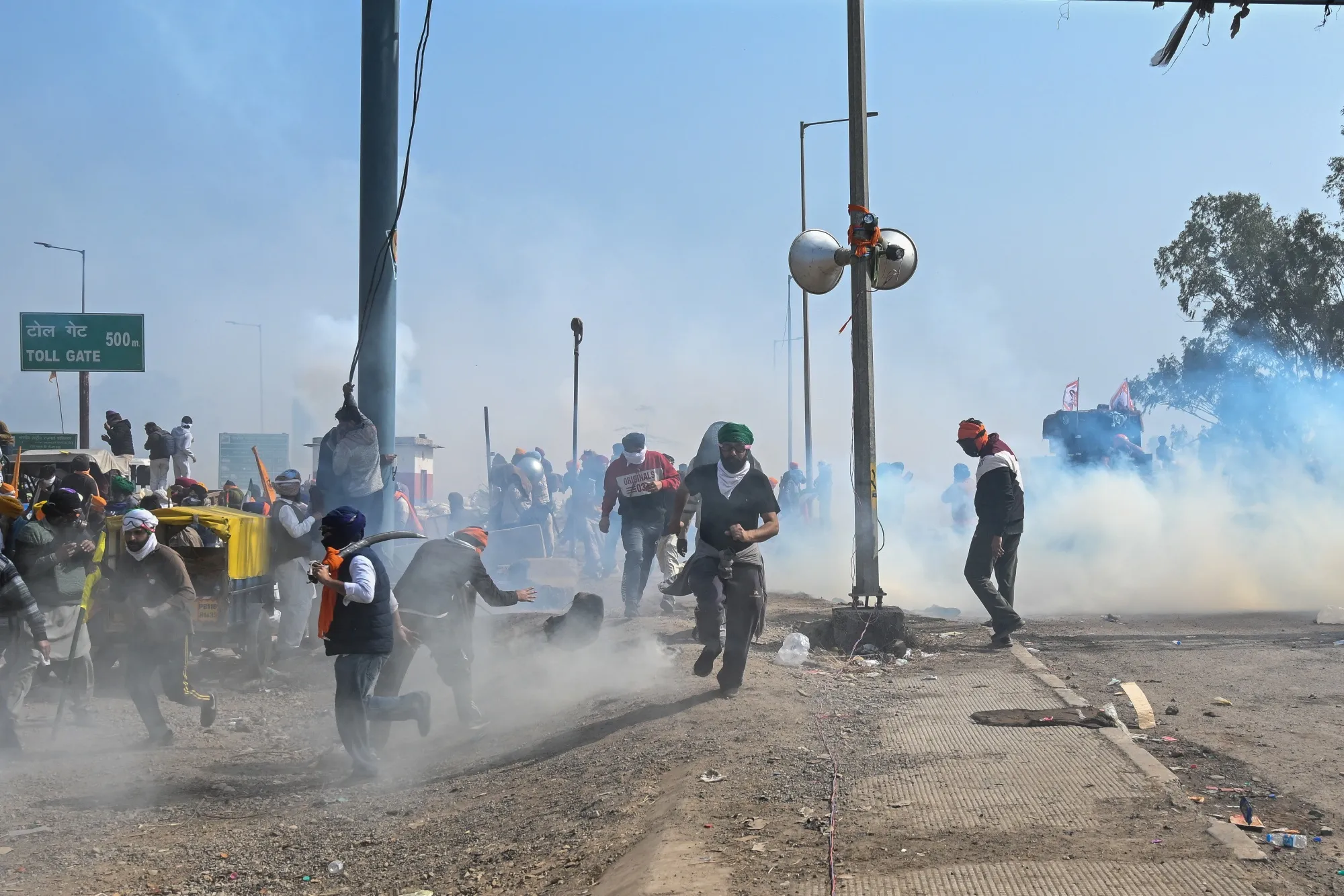 Demonstrators run for cover as police fire tear gas during a protest by farmers near the Haryana-Punjab state border in Rajpura, Punjab, India, on Feb. 21.