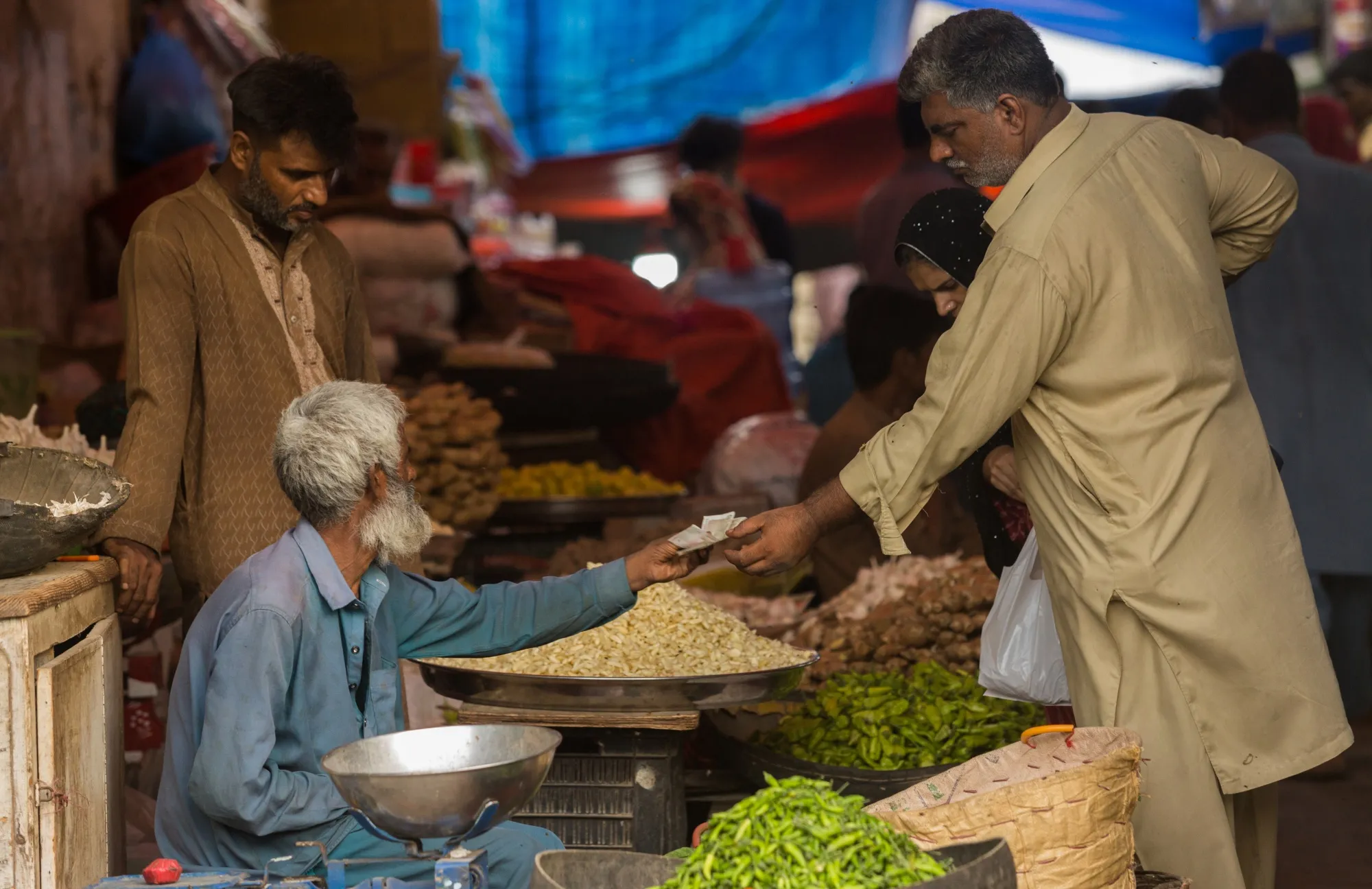 A vegetable vendor hands the Pakistani banknotes to a customer in Karachi, Pakistan.