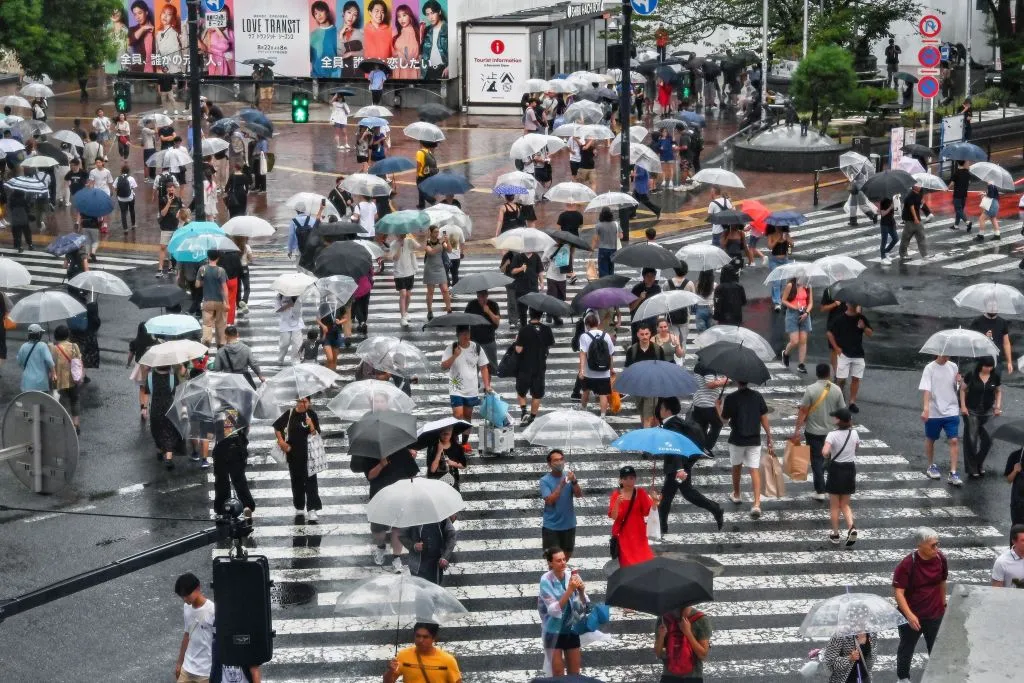 Pedestrians use their umbrellas to shelter from the rain while walking across Shibuya Crossing in central Tokyo.