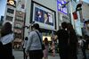 People wait for a traffic signal to change as a screen displays a live broadcast of Prime Minister Shinzo Abe speaking at a news conference in Tokyo, Japan, on Friday.