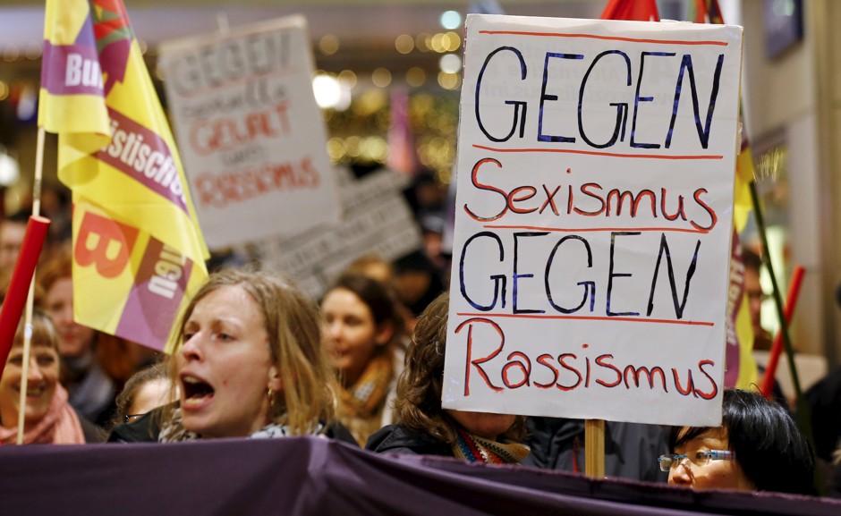 A woman holds up a sign that reads &quot;Against Sexism - Against Racism&quot; at the main railway station of Cologne, Germany, on January 5, 2016.