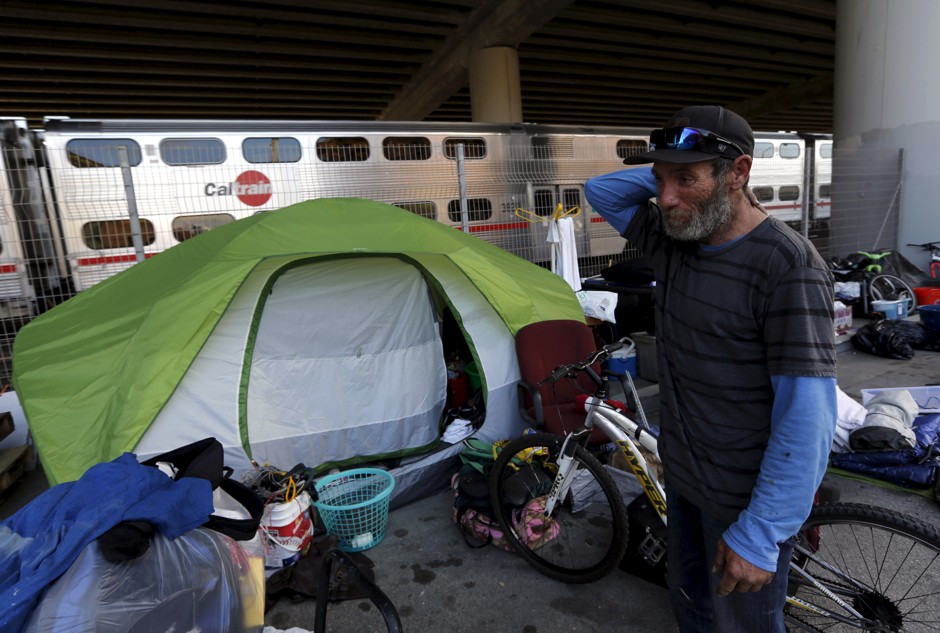 In this June photo, a man named Daryl stands outside his makeshift home near a housing construction project in San Francisco. The median rent for an apartment in the city is now $4,225 per month, according to local media.
