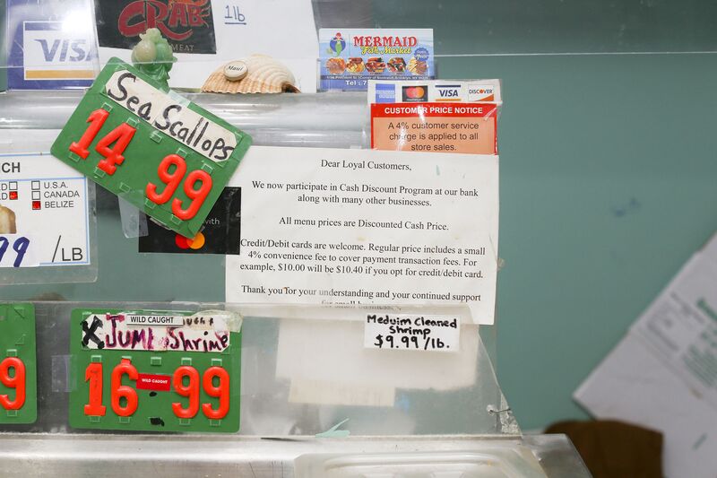 A sign alerts customers to a discount for cash transactions at Mermaid Fish Market in Brooklyn, N.Y.