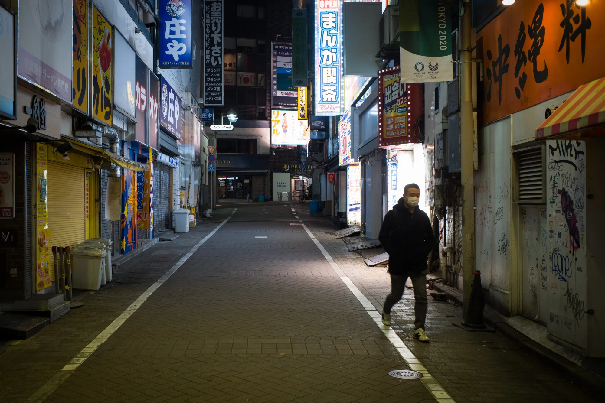 A person wearing a protective mask walks past closed restaurants in the Shibuya district of Tokyo.