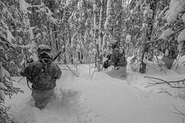 Soldiers maneuver through nearly waist-deep snow as they simulate an attack on a defensive position.