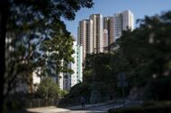 A man jogs past residential buildings in this photograph taken with a tilt-shift lens in the Mid-Levels area of Hong Kong, China, on Friday, Nov. 27,  2015. Secondary private residential property prices dropped 3.9 percent since peaking in September, according to an index published by broker Centaline Property Agency Ltd. Photographer: David Paul Morris/Bloomberg