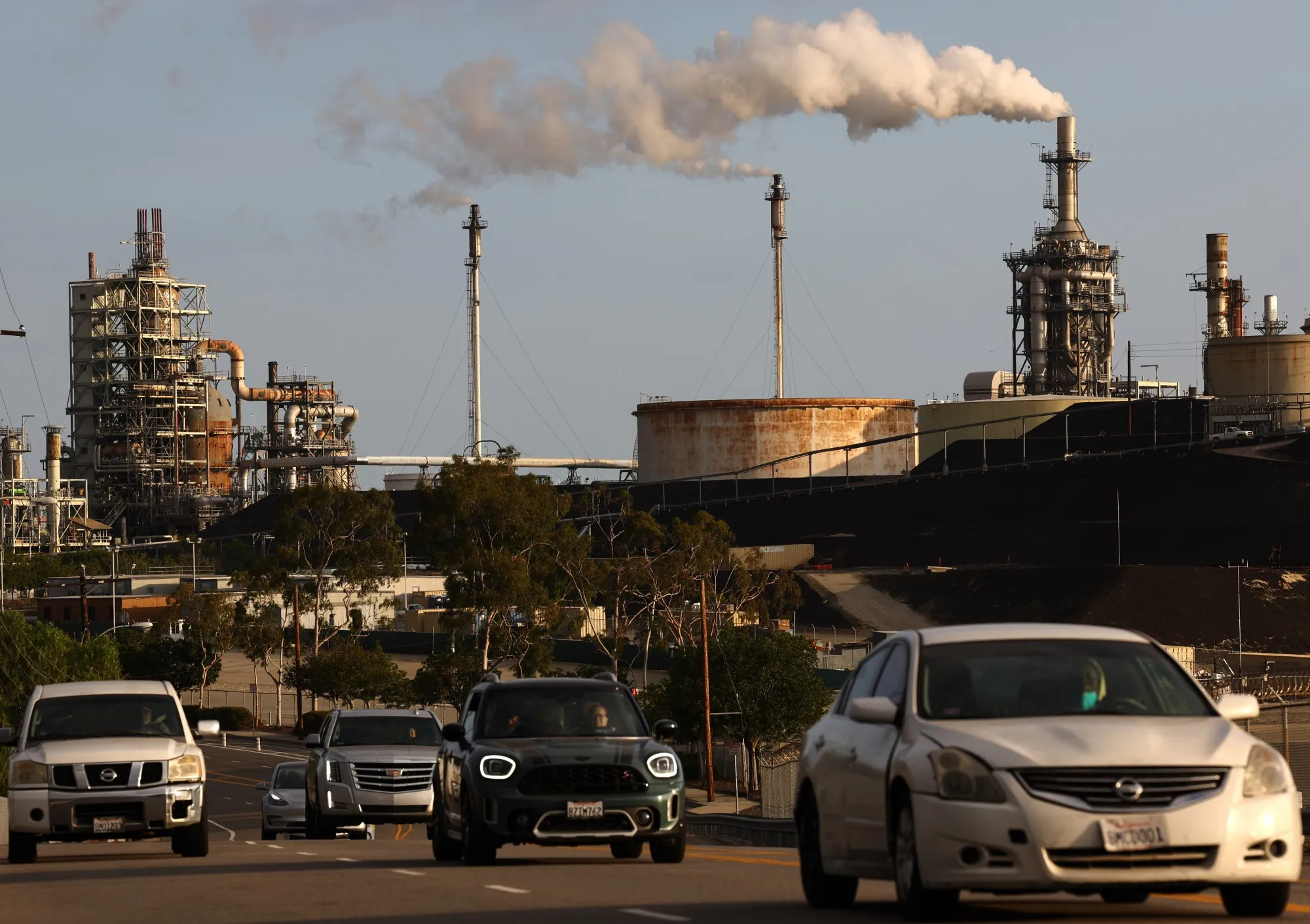 Vehicles pass tan oil refinery&nbsp;in Wilmington, California.&nbsp;