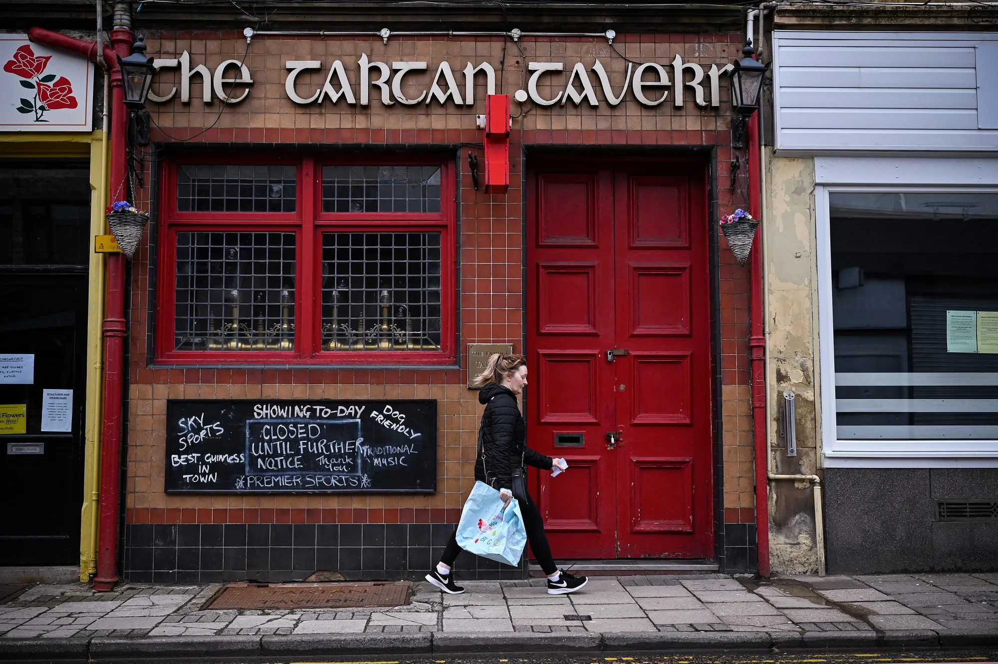 A pedestrian walks past a closed pub&nbsp;in Oban, Scotland.