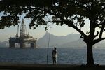 A man fishes in Guanabara Bay while an oil drilling platform floats in the background near Niteroi, Brazil.