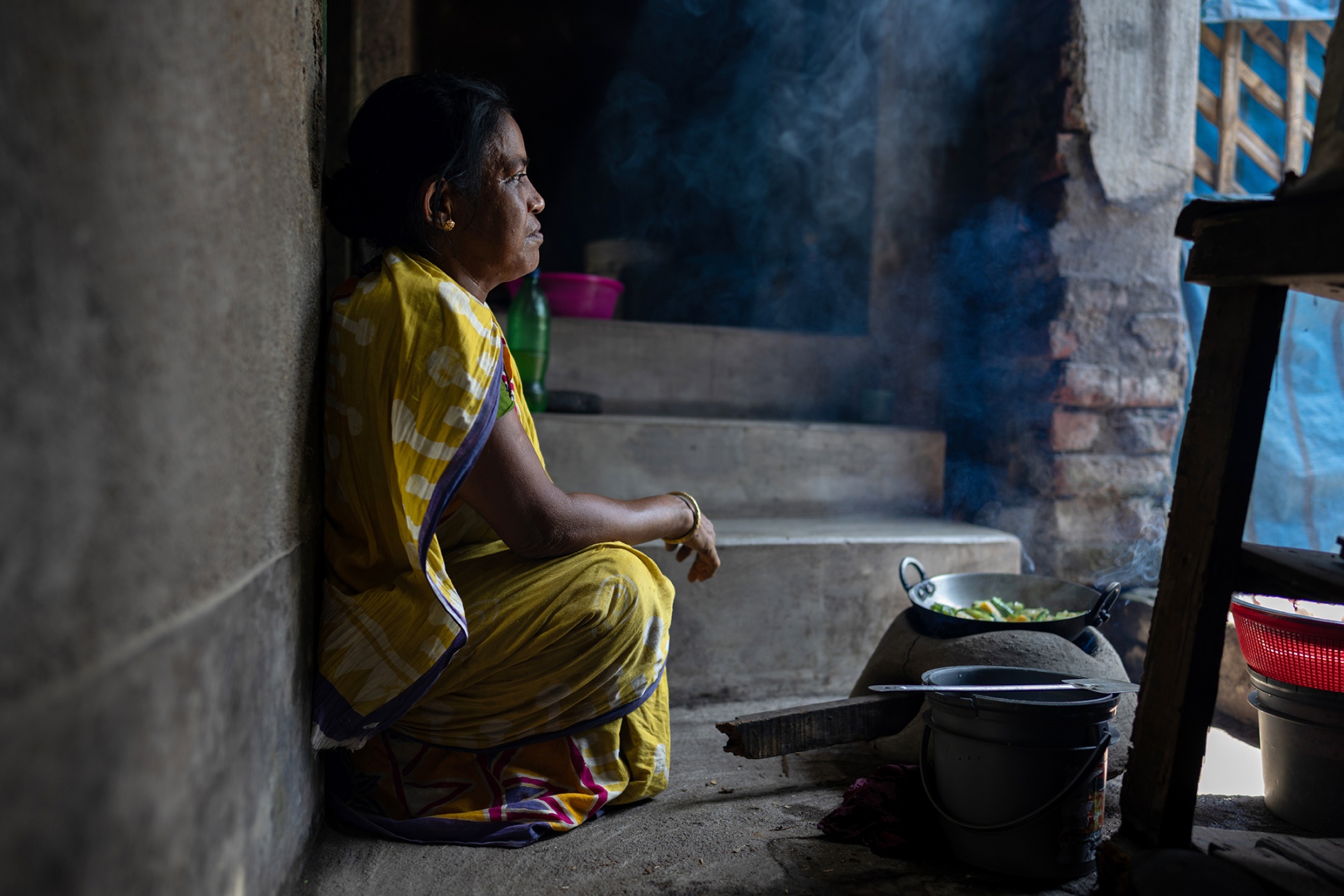A homemaker cooks on a traditional clay stove.