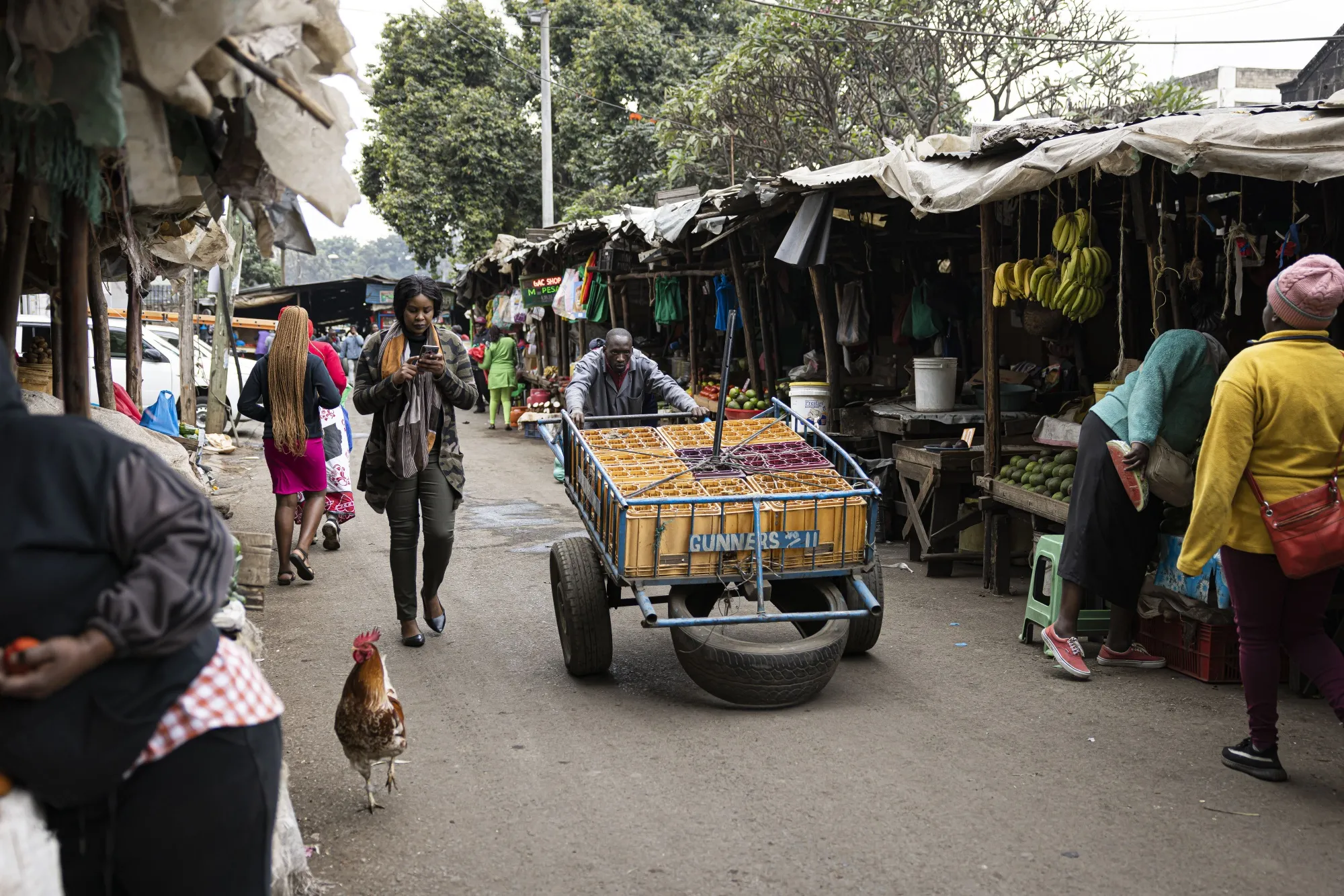 A worker pushes a cart past market stalls in Nairobi, Kenya.