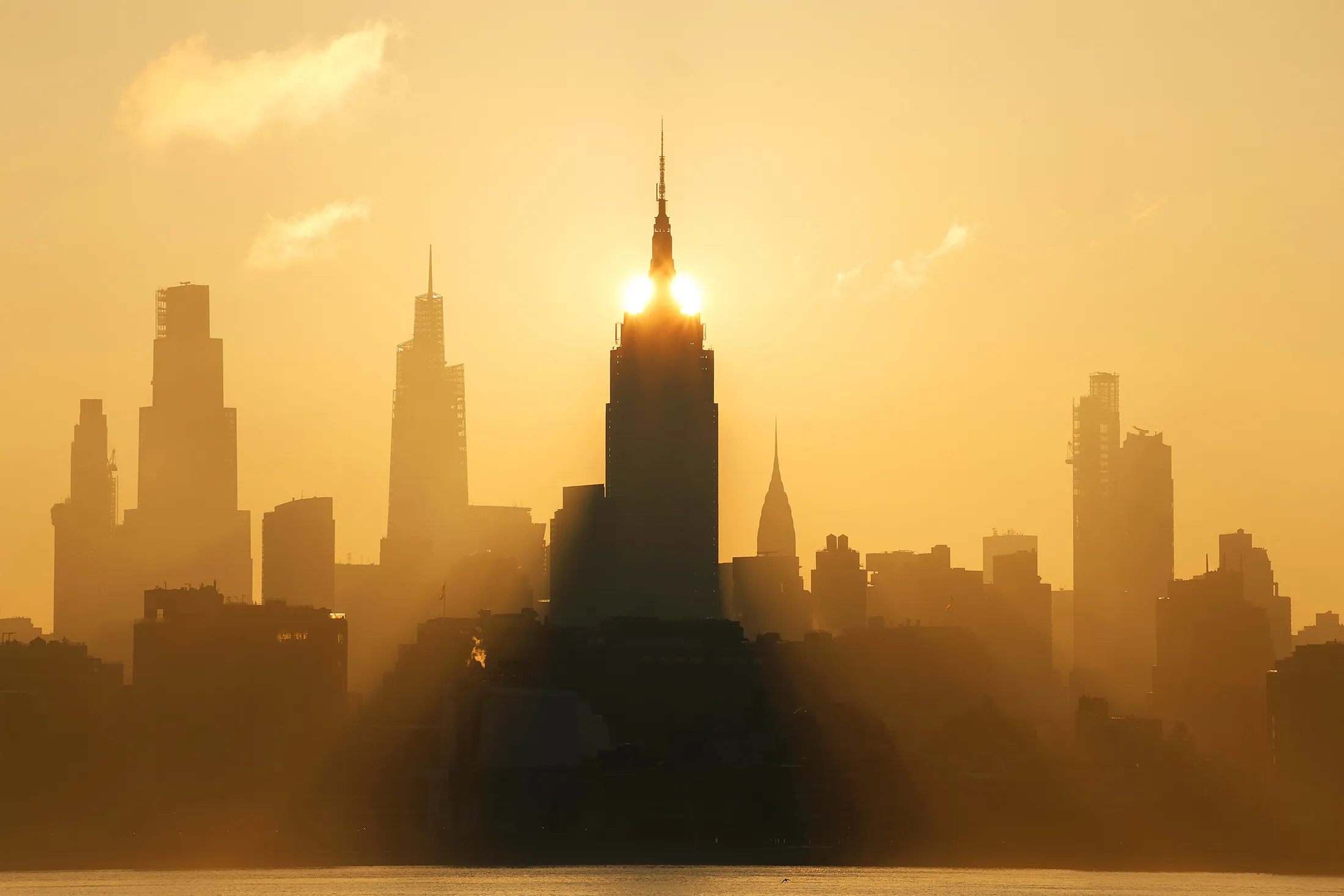 The sun rises behind the skyline of midtown Manhattan and the Empire State Building in New York City on June 19.