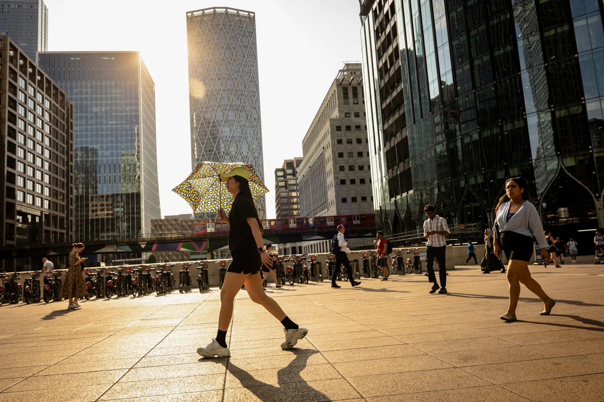 A pedestrian uses a umbrella to protect herself from the sun, at Canary Wharf, during a heatwave in London, UK, on Monday, July 18, 2022.&nbsp;