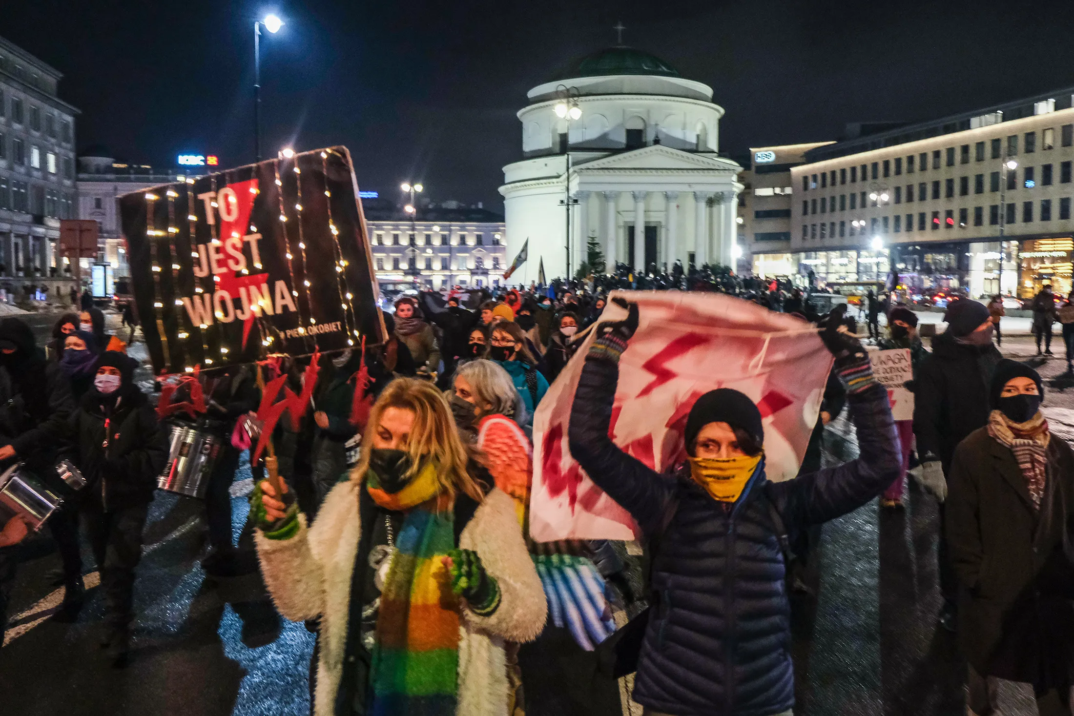 Demonstrators wearing protective masks hold banners during a protest in Warsaw on Jan. 20.