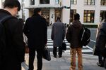 Morning commuters wait to cross a road in front of Tokyo Station in Tokyo.