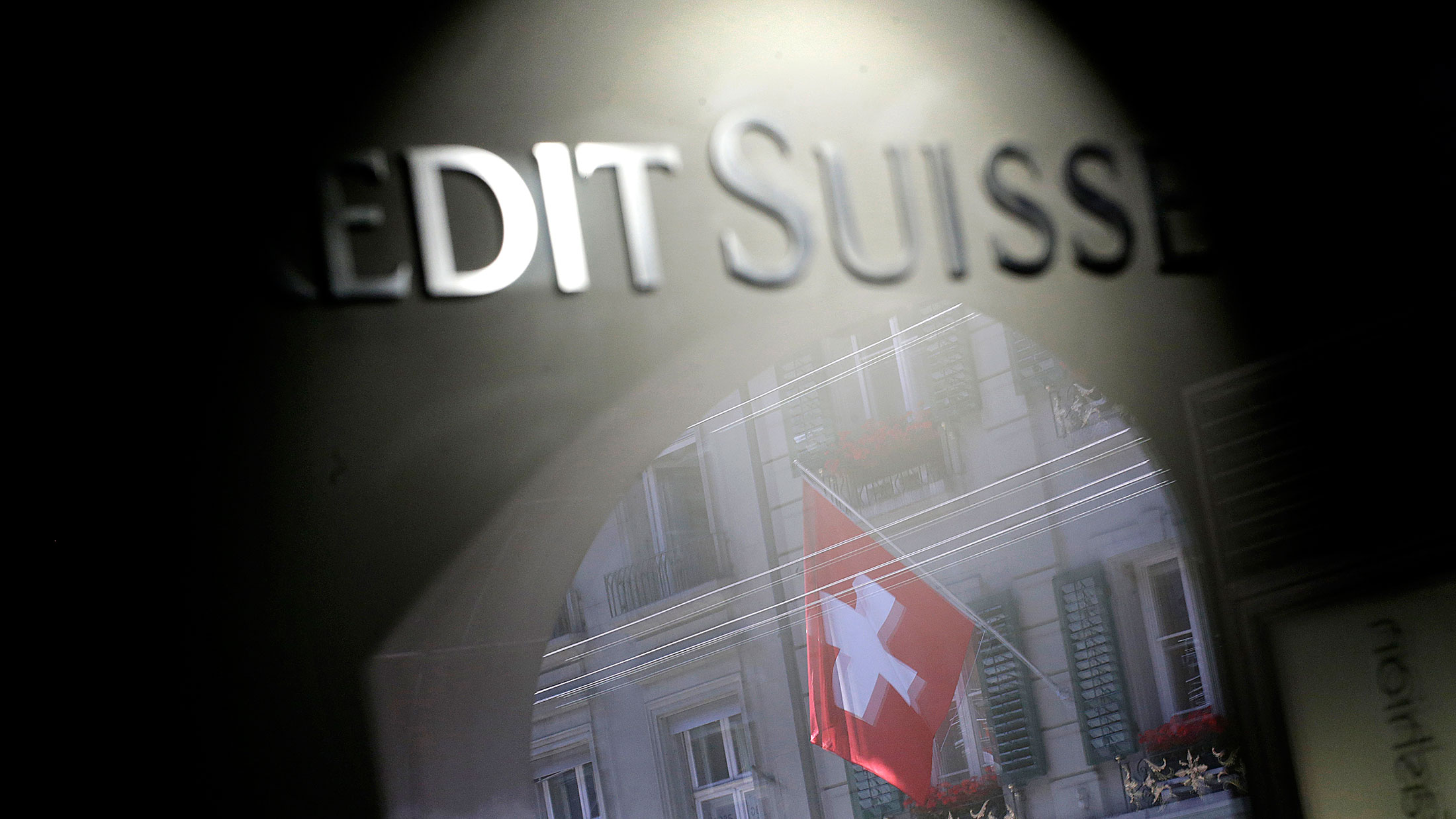 The Swiss national flag is seen reflected in the window of a Credit Suisse Group AG bank branch in Bern, Switzerland.
