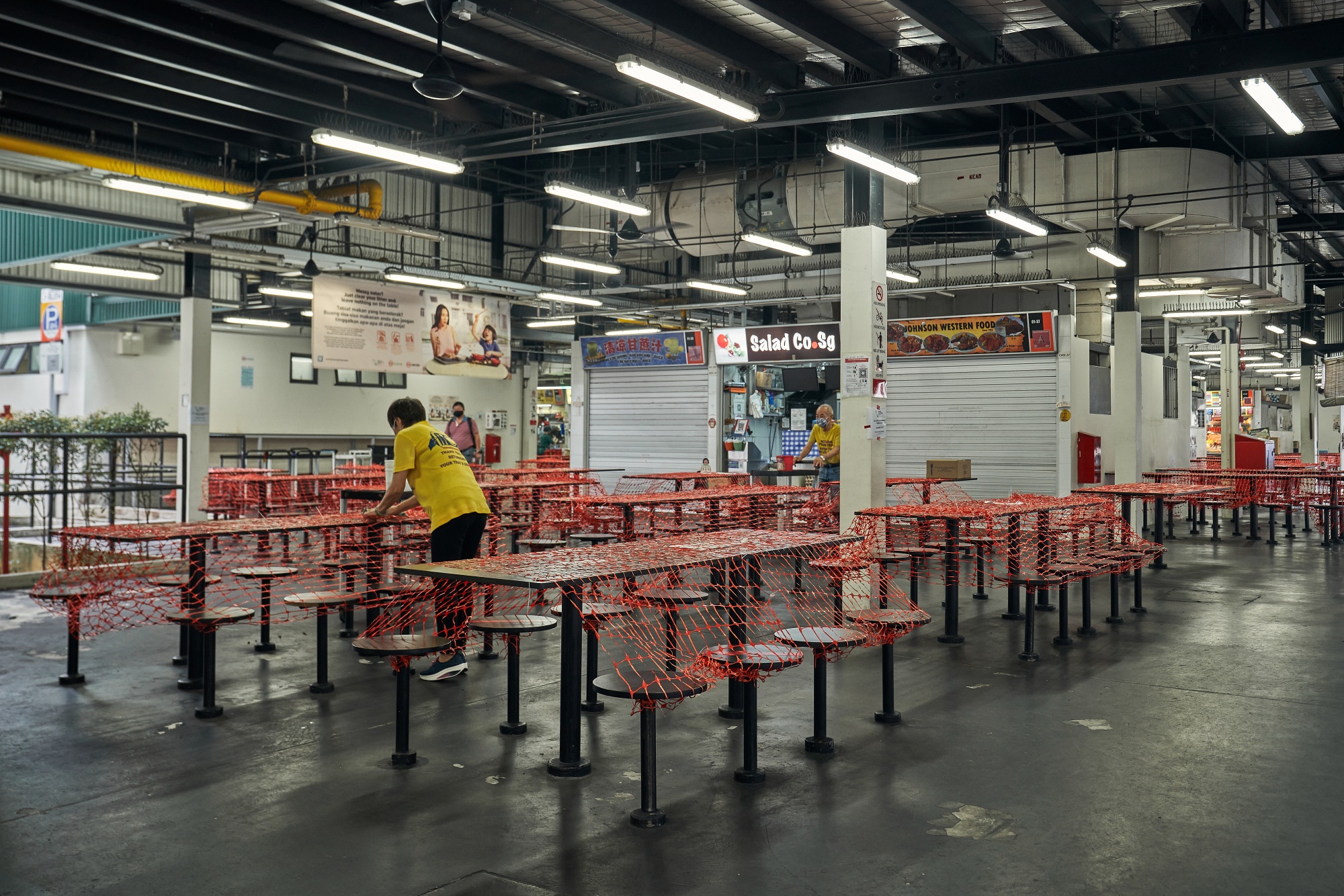 A worker covers tables making them unavailable in front of eateries in Singapore on May 19.