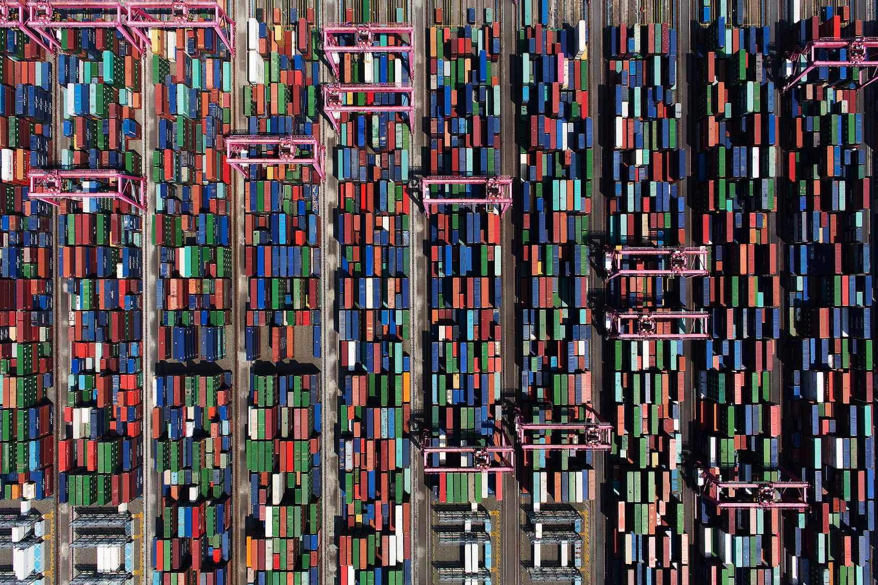 Shipping containers sit stacked among gantry cranes in this aerial photograph taken above the BNCT Co. container terminal at Busan New Port in Busan, South Korea, on Thursday, July 30, 2015. South Korea is scheduled to release trade figures on Aug. 1.
