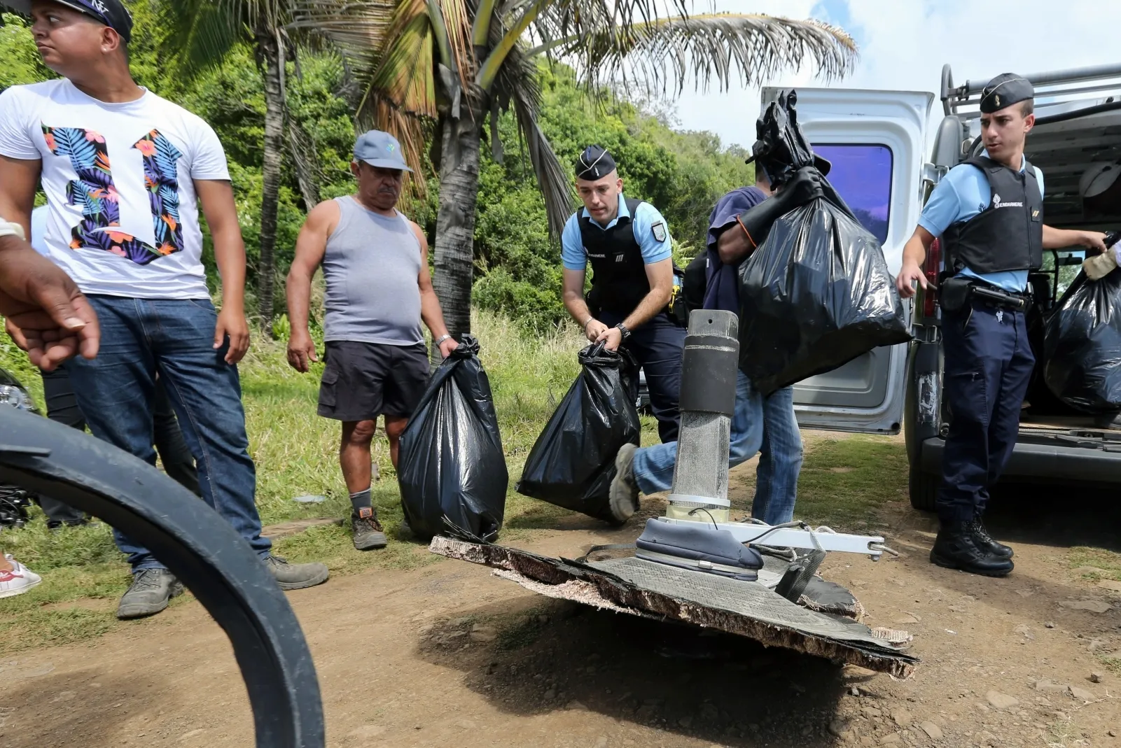 French Gendarmes and local volunteers carry bags of debris gathered on Reunion island, on August 11, 2015.
