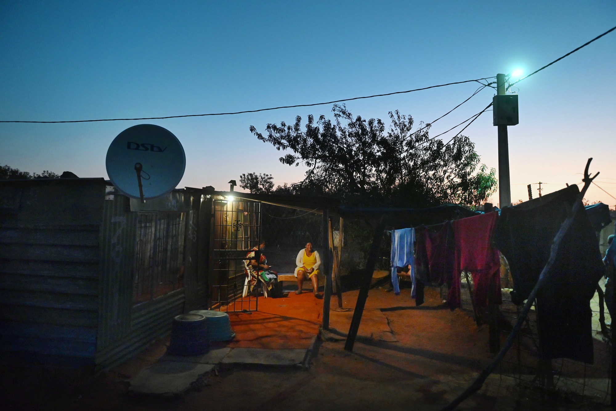 Residents sit outside a home in Slovo Park.