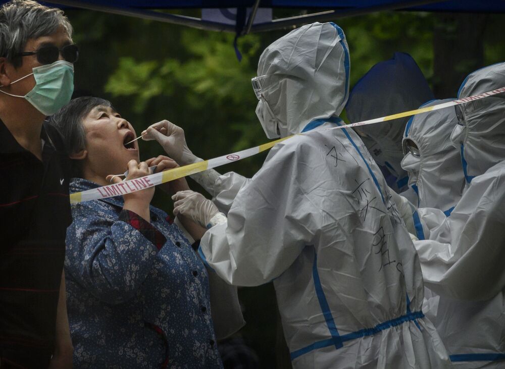 An epidemic control worker conducts a nucleic acid test for Covid-19 on a woman at a testing center in Beijing on June 20.
