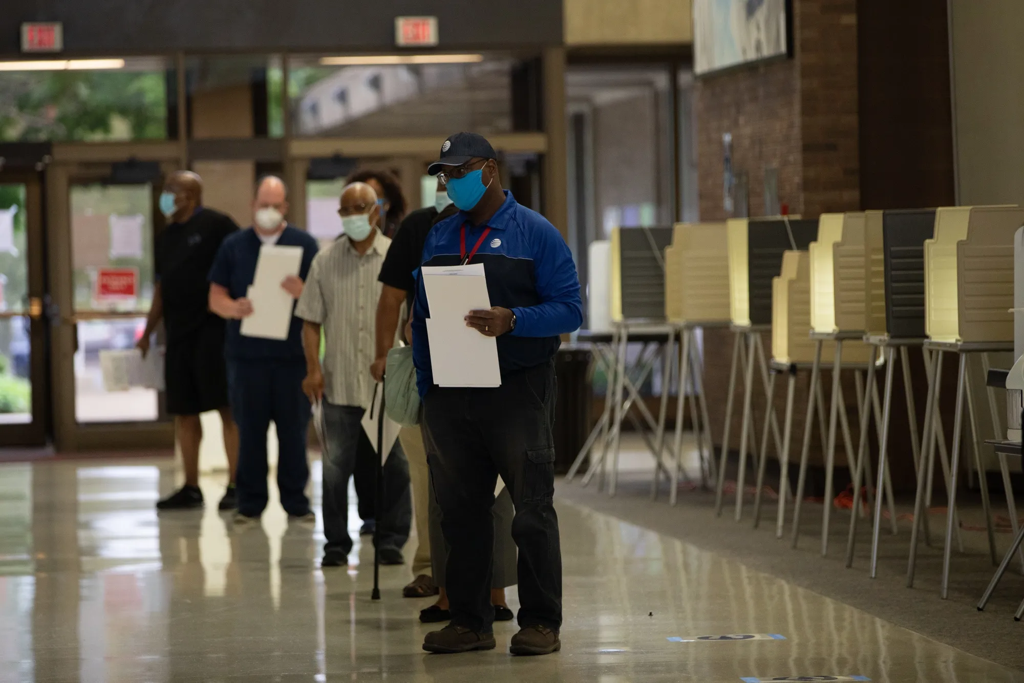 Voters wearing protective masks stand in line to submit ballots at a polling location in Southfield, Michigan.