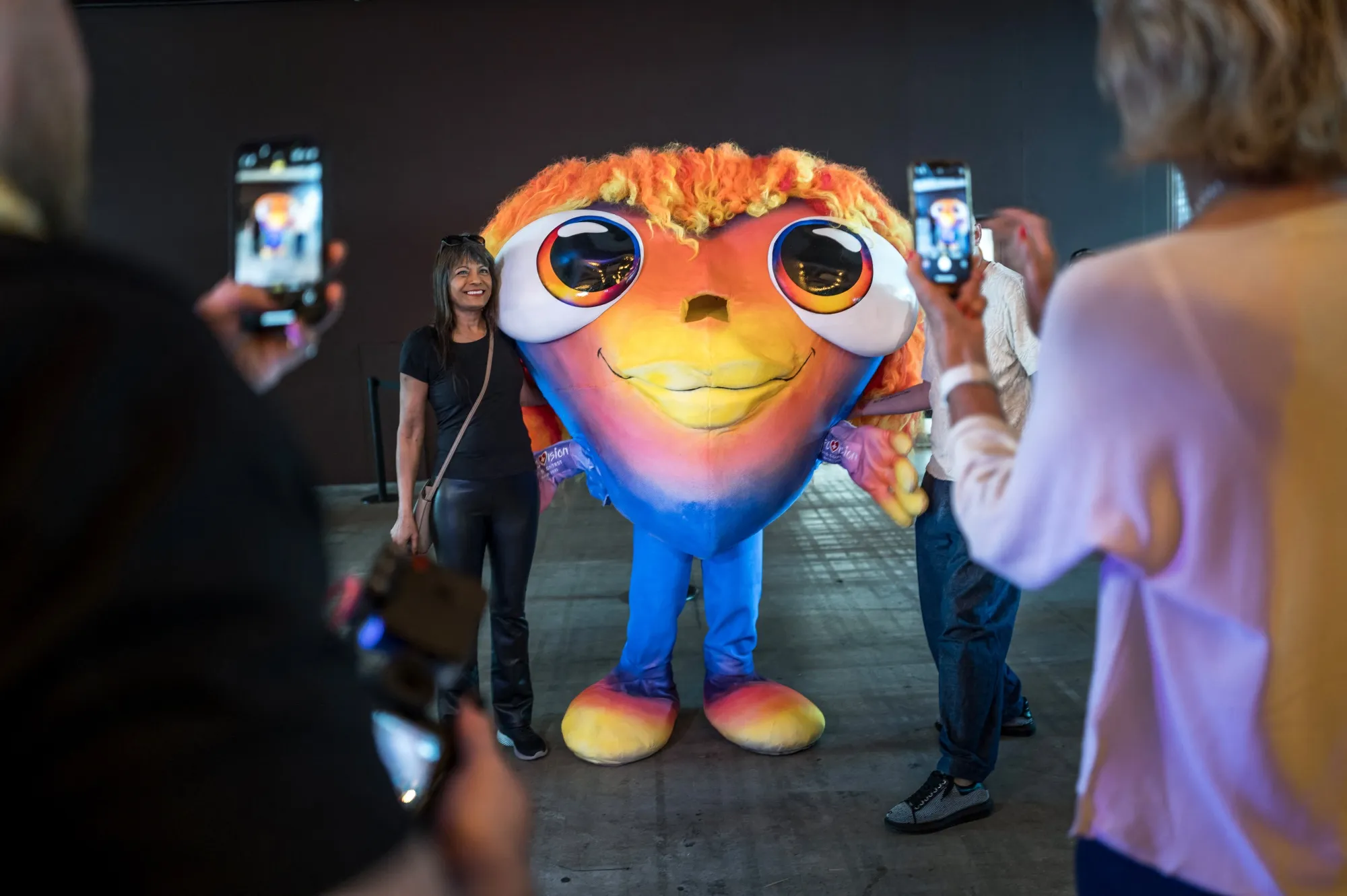 Visitors take photographs with the Eurovision Song Contest 2025 mascot in Basel, Switzerland.