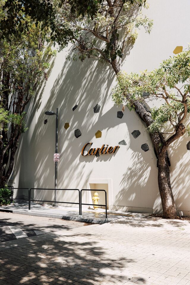 A close up of Cartier gold signage with white exterior. 