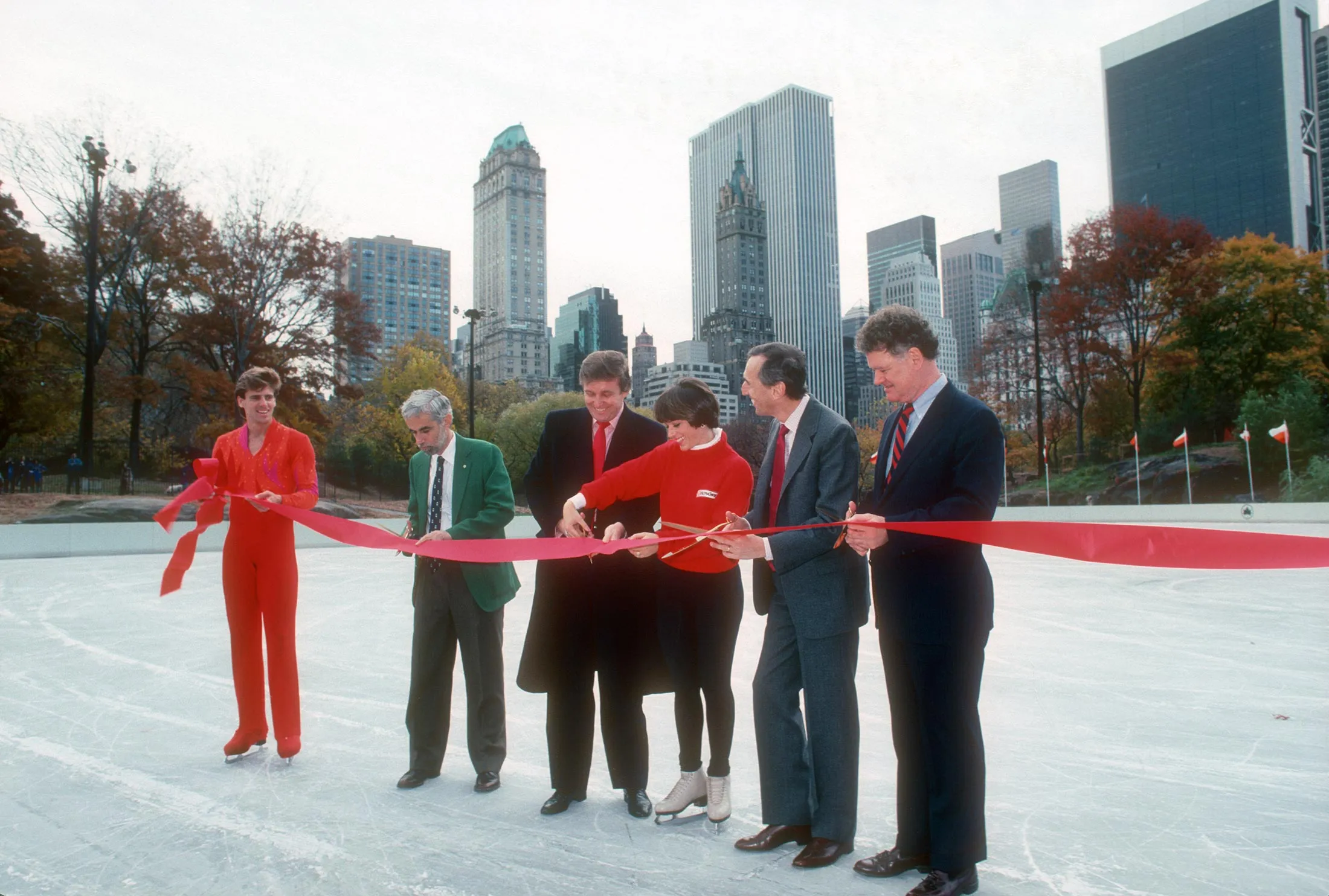 Nov 1, 1986 - New York City, New York, U.S. - Donald Trump holds the red ribbon steady while Olympic ice skating champion Dorothy Hamill and Scott Hamilton cut it during a gala ceremony down in the sunken, tree-shrouded gulch just off Central Park South to celebrate the finished renovation of the Wollman Ice-Skating Rink in Central Park. Trump paid for the entire renovation out of his own pocket, with the understanding that he'd be reimbursed upon completion up to an agreed-upon limit. The finished rink came in at US1.95 million, Trump said, which was US750,000 below the limit.
