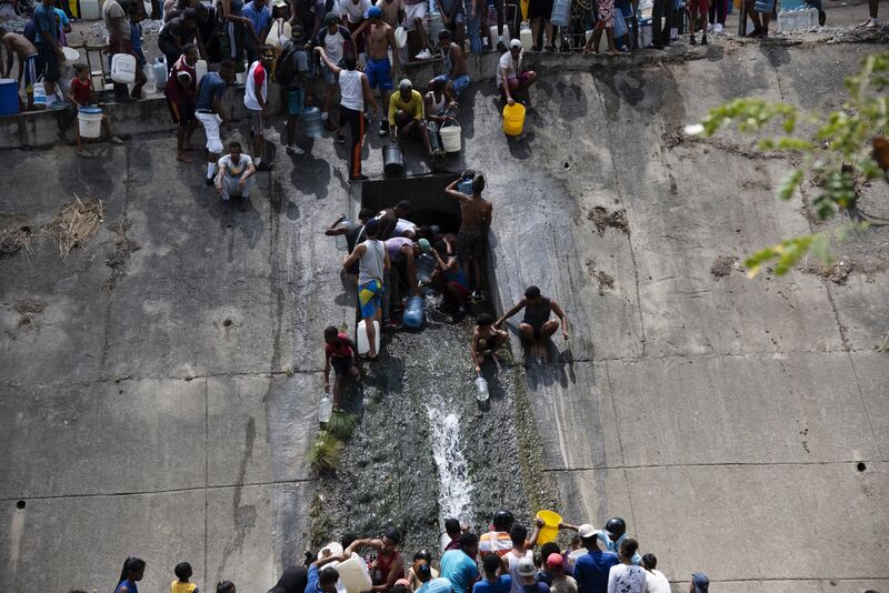Residents of San Agustin taking water from a a drainage pipe in the Guaire river west of Caracas on March 11.