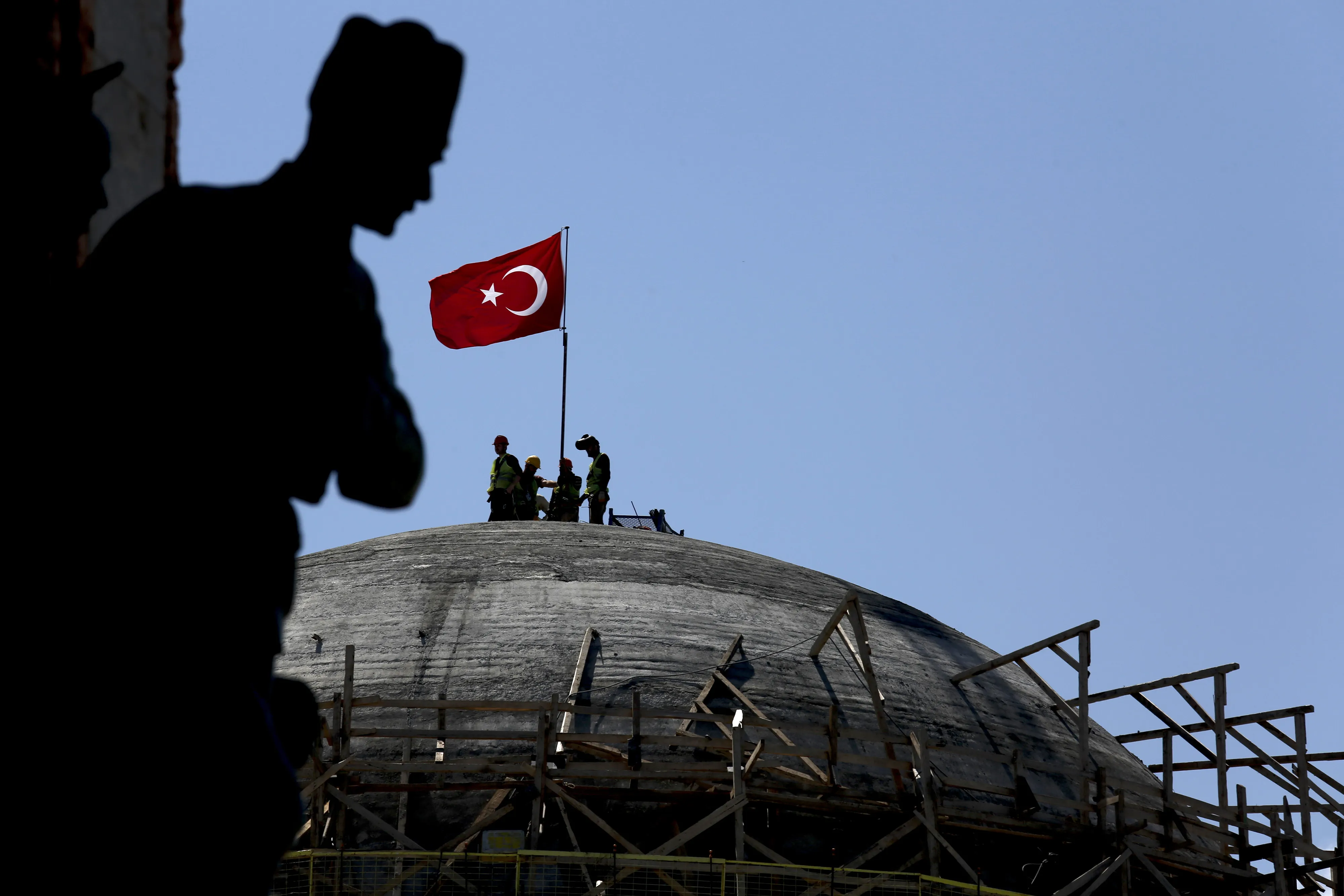 Construction workers place a Turkish national flag on the dome of&nbsp; mosque in&nbsp;Istanbul.