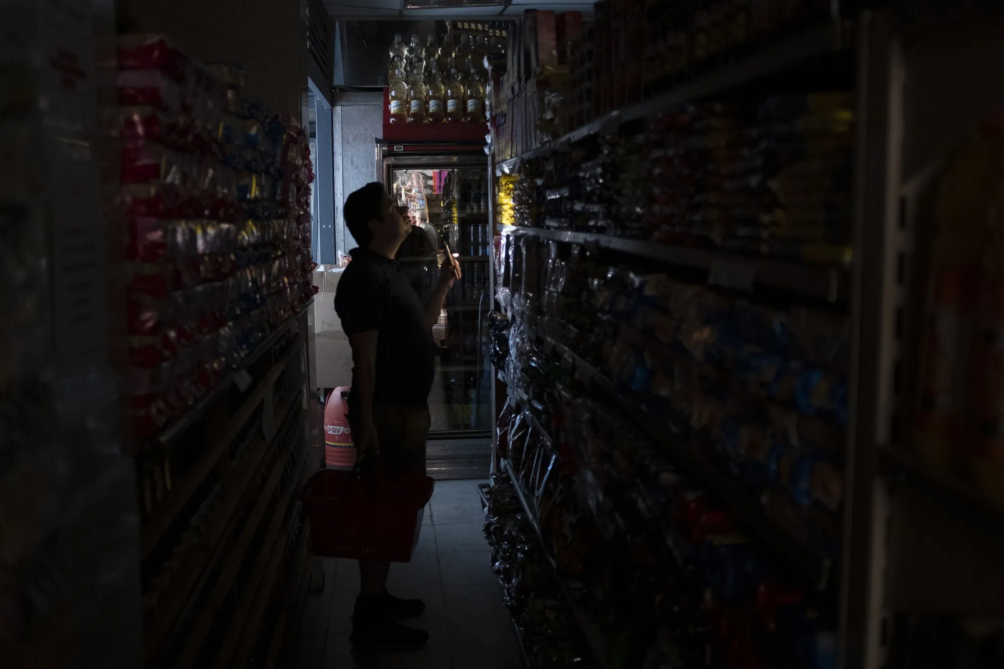 A person uses a mobile phone to illuminate goods at a supermarket during a power outage in Caracas on March 10.