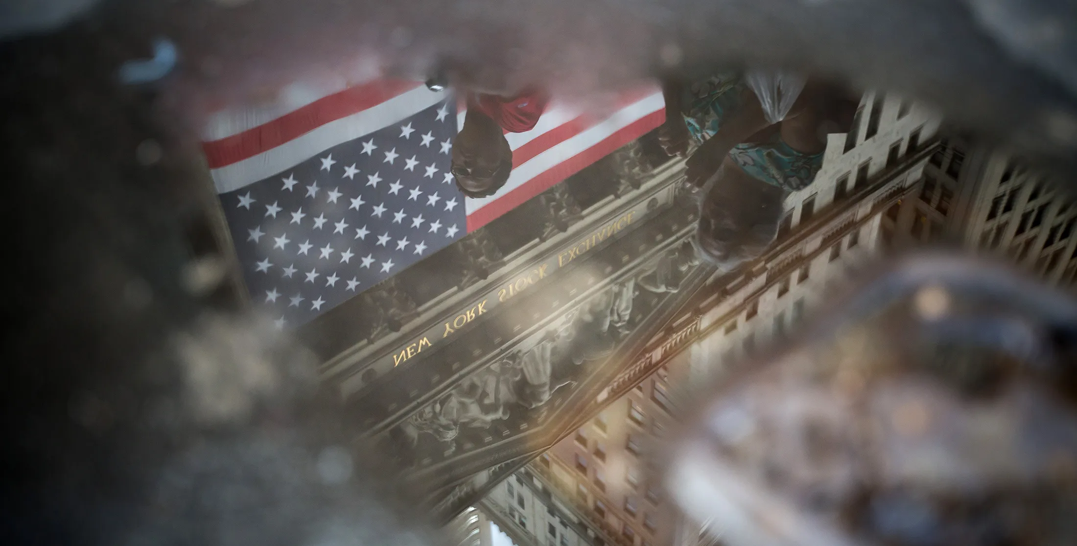 The New York Stock Exchange is reflected in a puddle.
