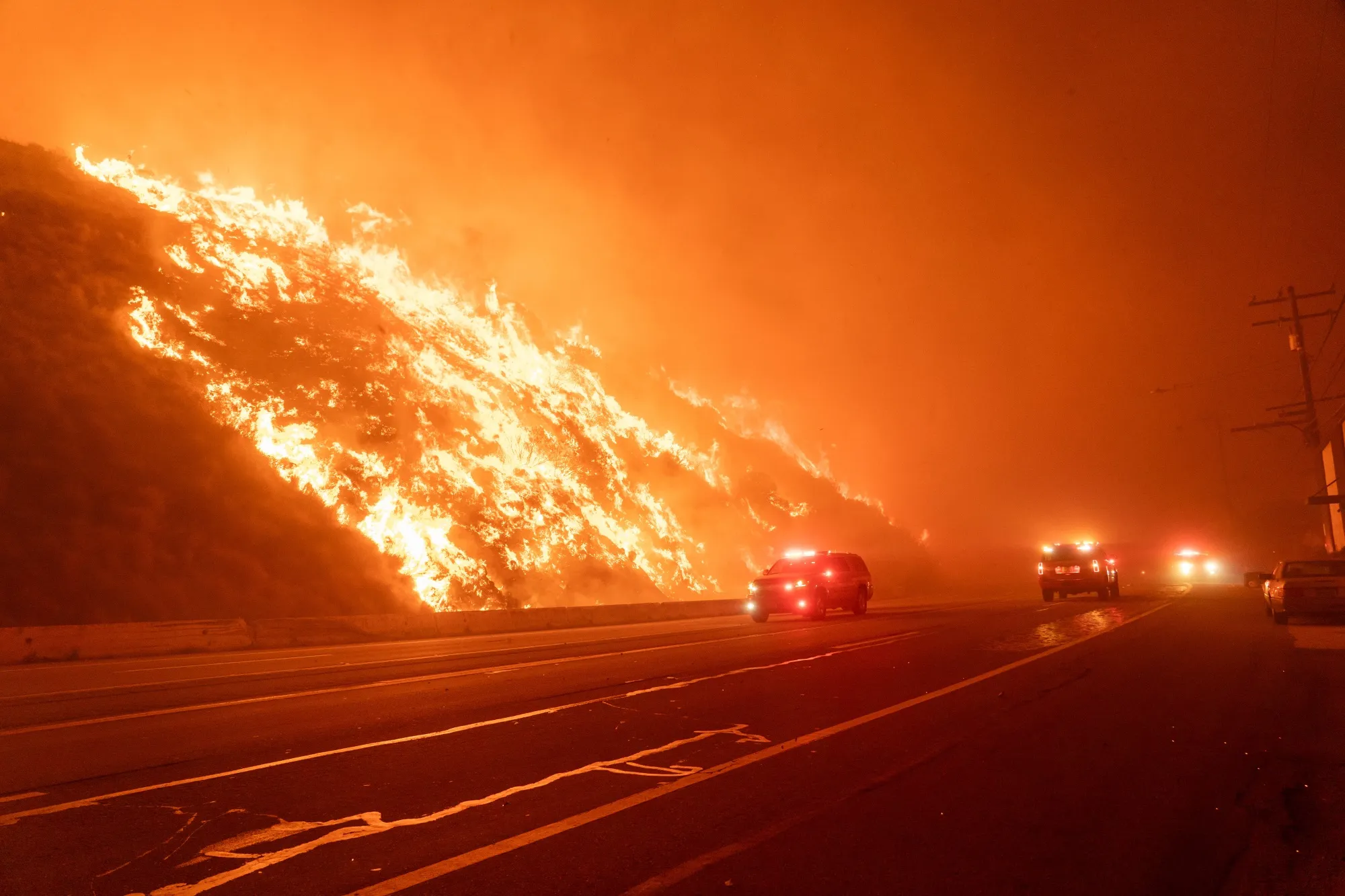 Emergency workers drive past the Palisades fire on Jan. 7.
