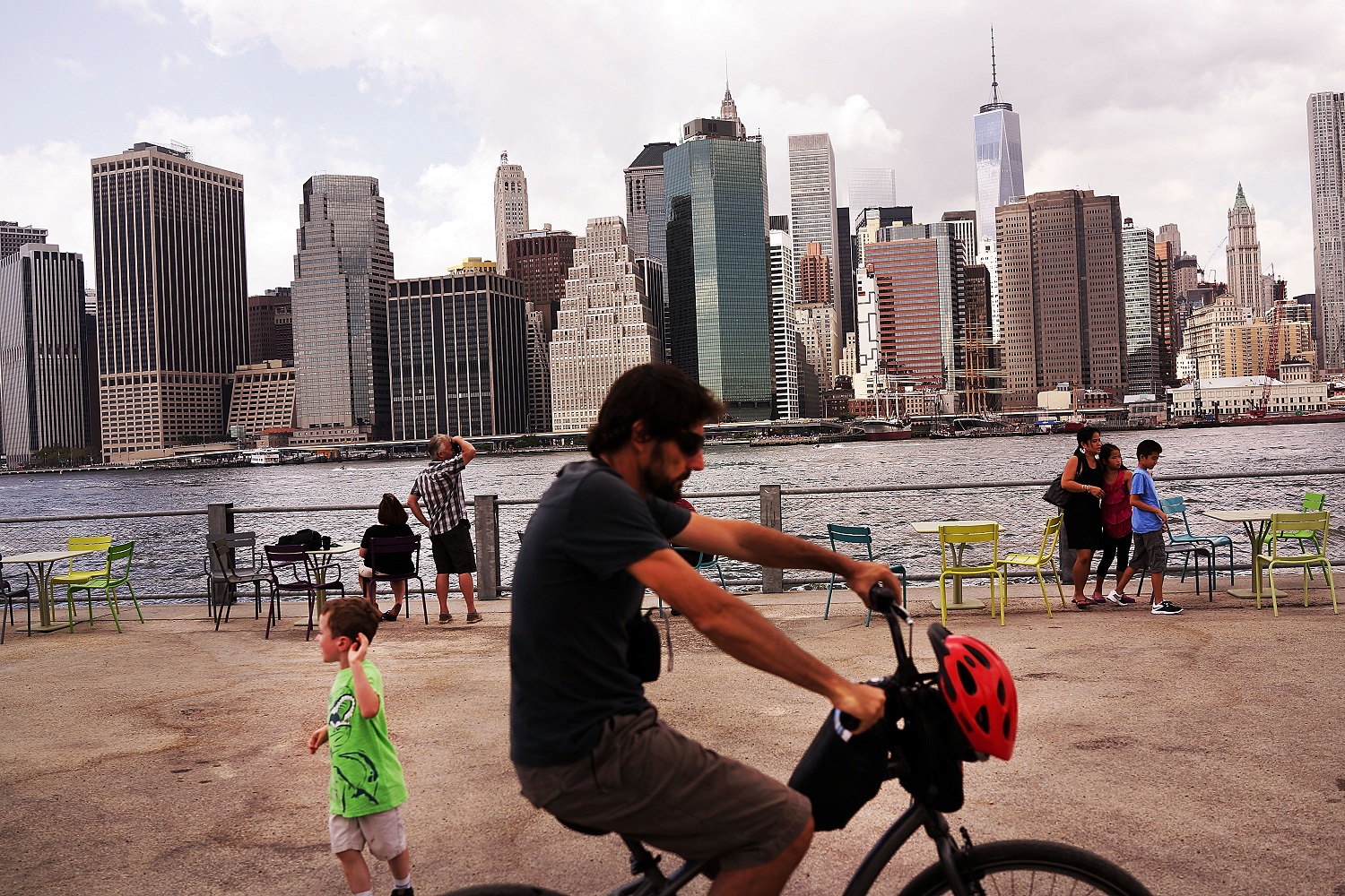 The Manhattan skyline is seen in the background as people relax in the Brooklyn Bridge Park in the Brooklyn borough of New York City. Photographer: Spencer Platt/Getty Images