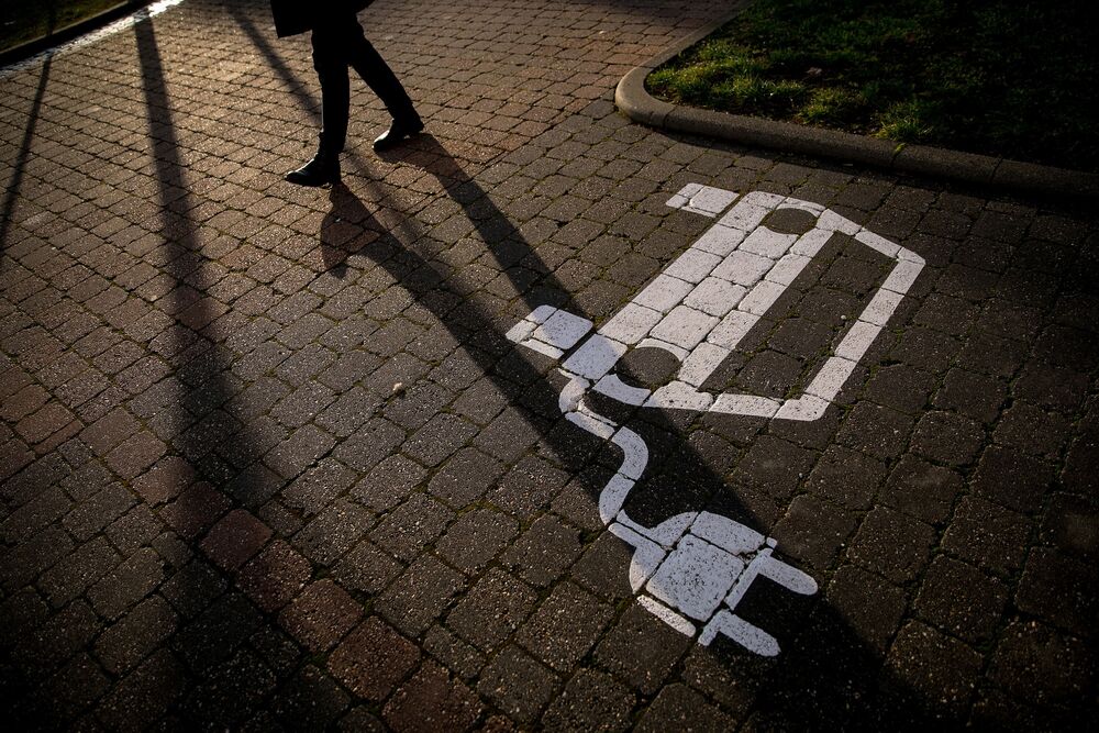 A pedestrian passes an empty electric vehicle charge space in a parking lot in Gruenheide, Germany.
